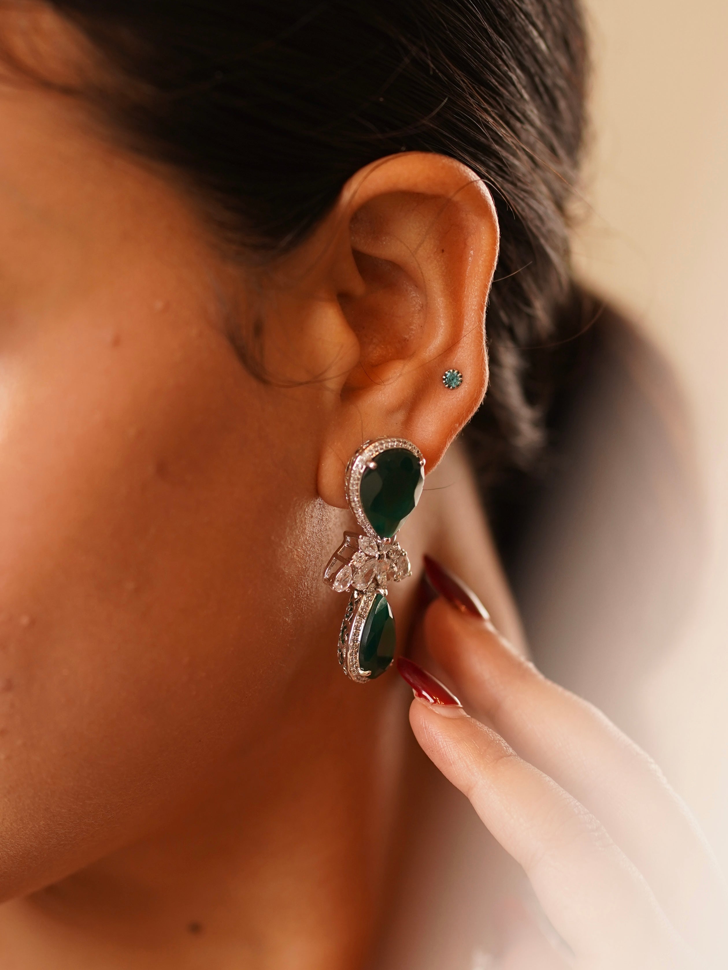 close‑up of emerald teardrop pendant bordered by brilliant‑cut cubic zirconia