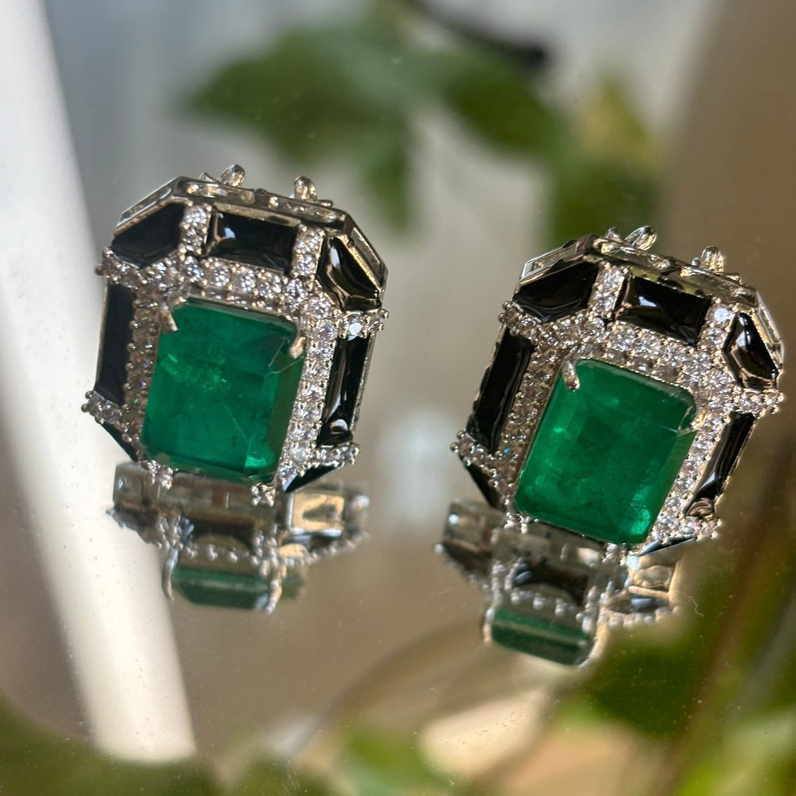 close-up of thin chain, enamel pendant and ring in emerald doublet set on white background