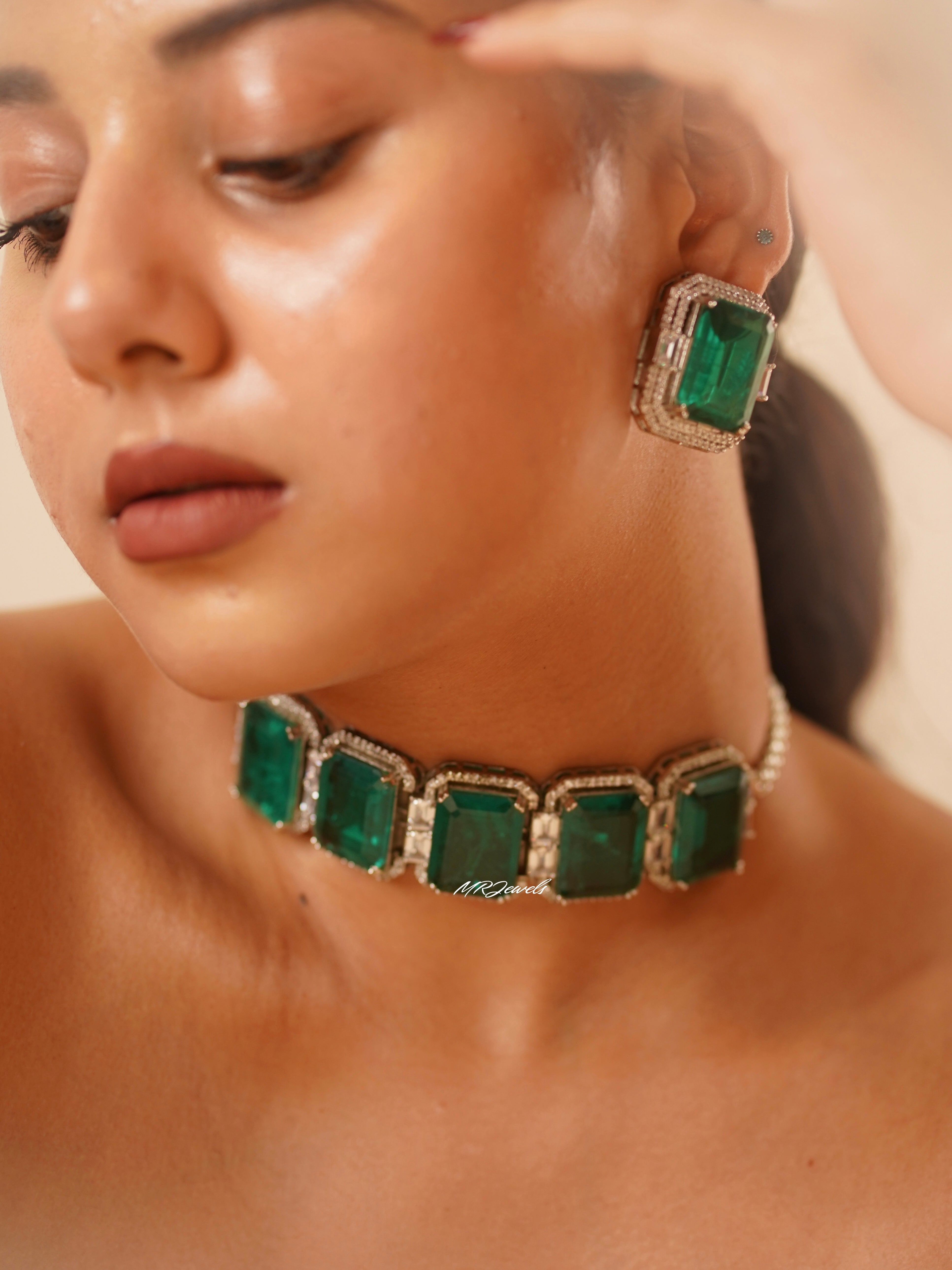 Angled view of emerald choker and studs showing geometric layout and bold green gem finish