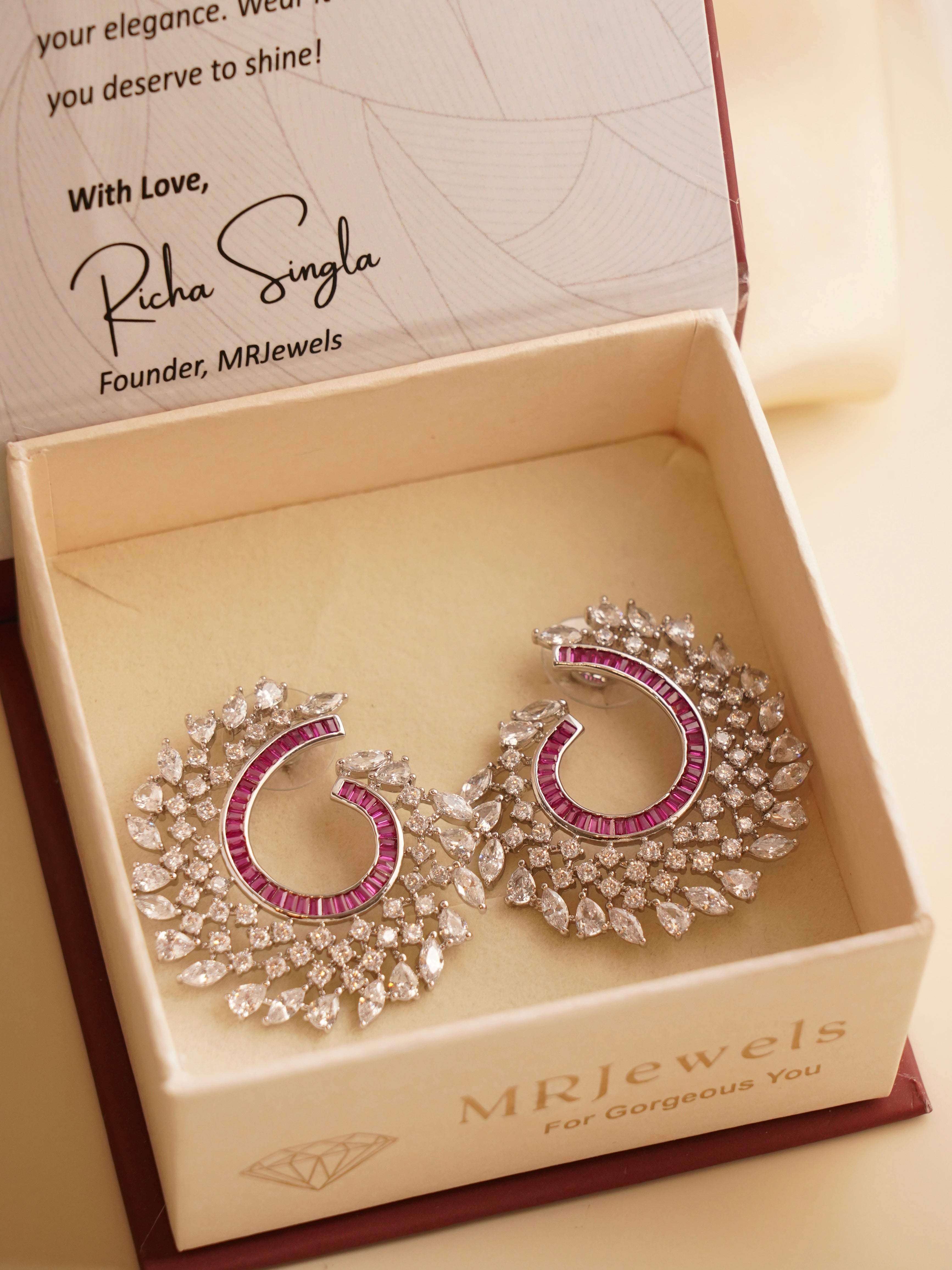 Front-facing spiral earrings encrusted with hand-set zircon, emerald, ruby and sapphire baguette stones