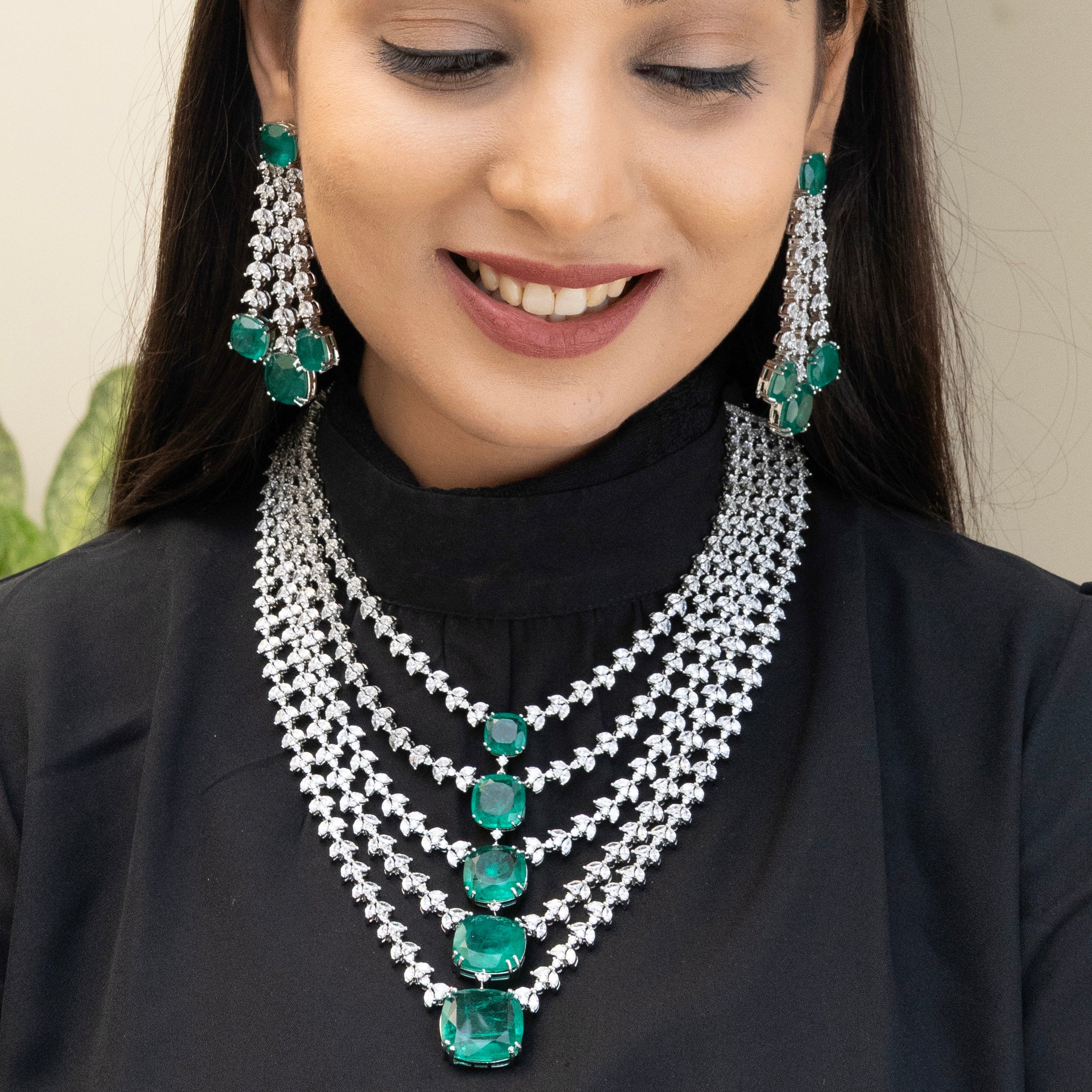 Side angle of layered emerald necklace set showcasing sparkle and depth