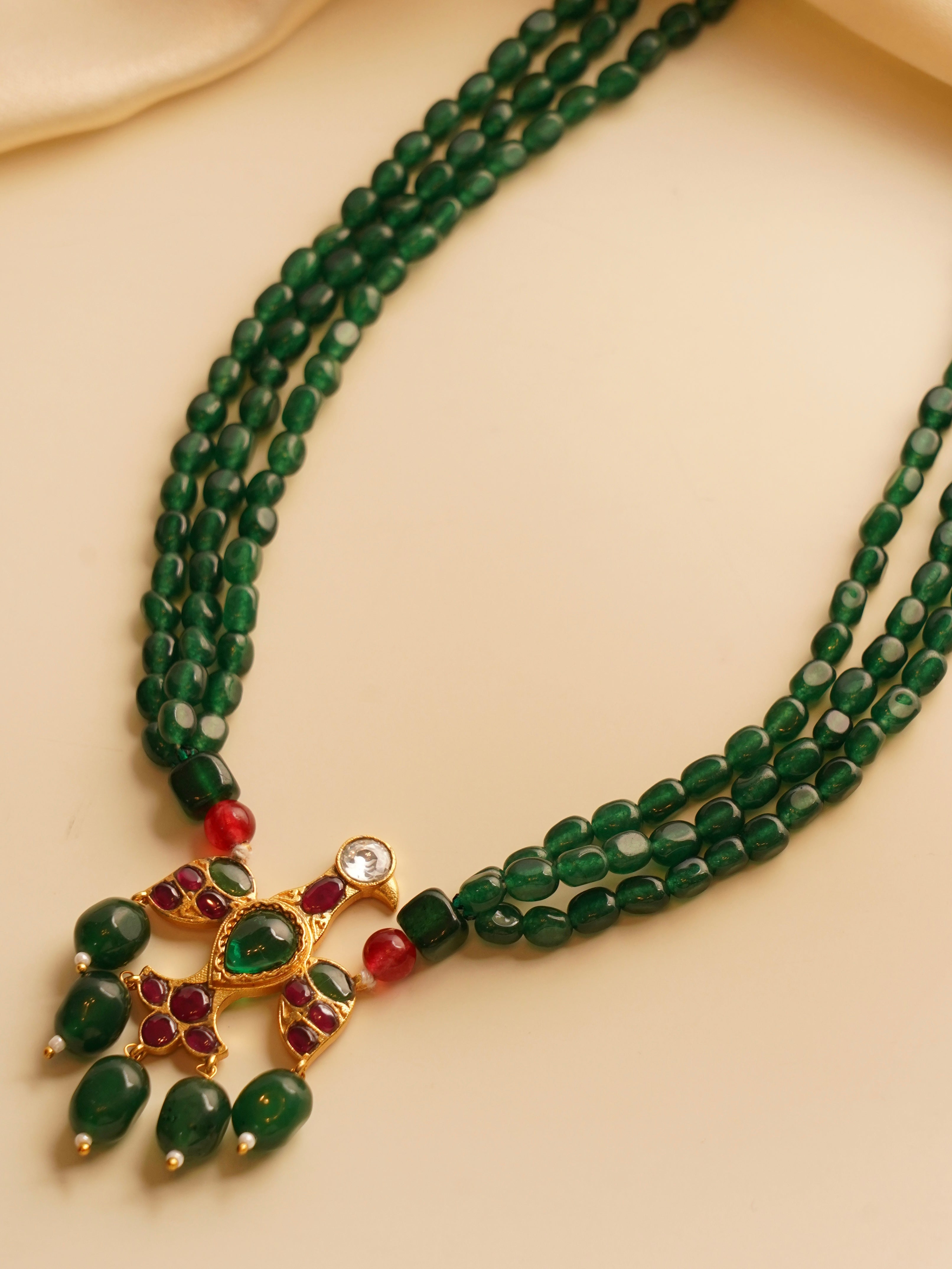 Top view of triple-strand emerald necklace with eagle design pendant