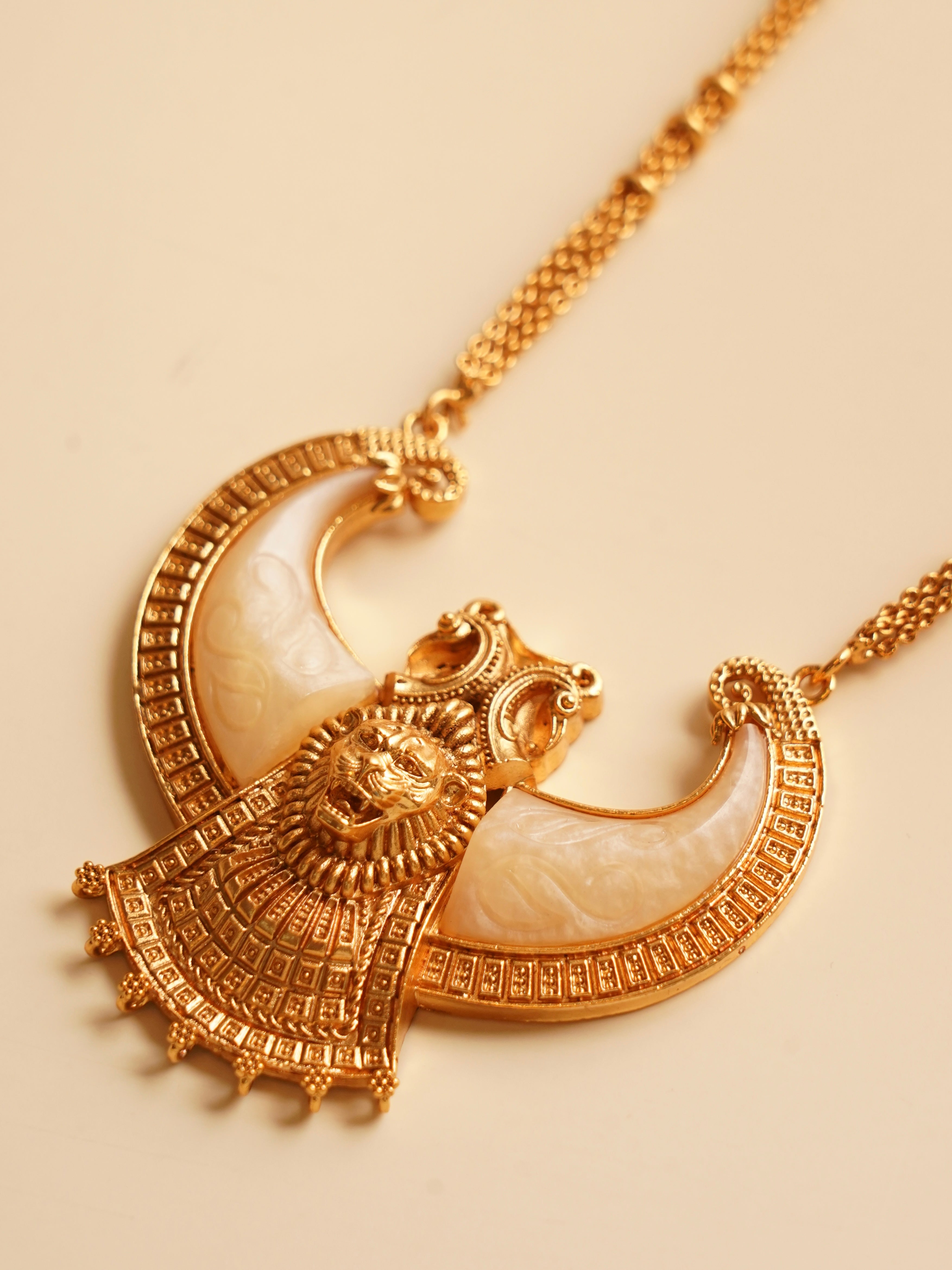 Designer necklace with lion motif, gold detailing, and crescent-shaped white stone inlays