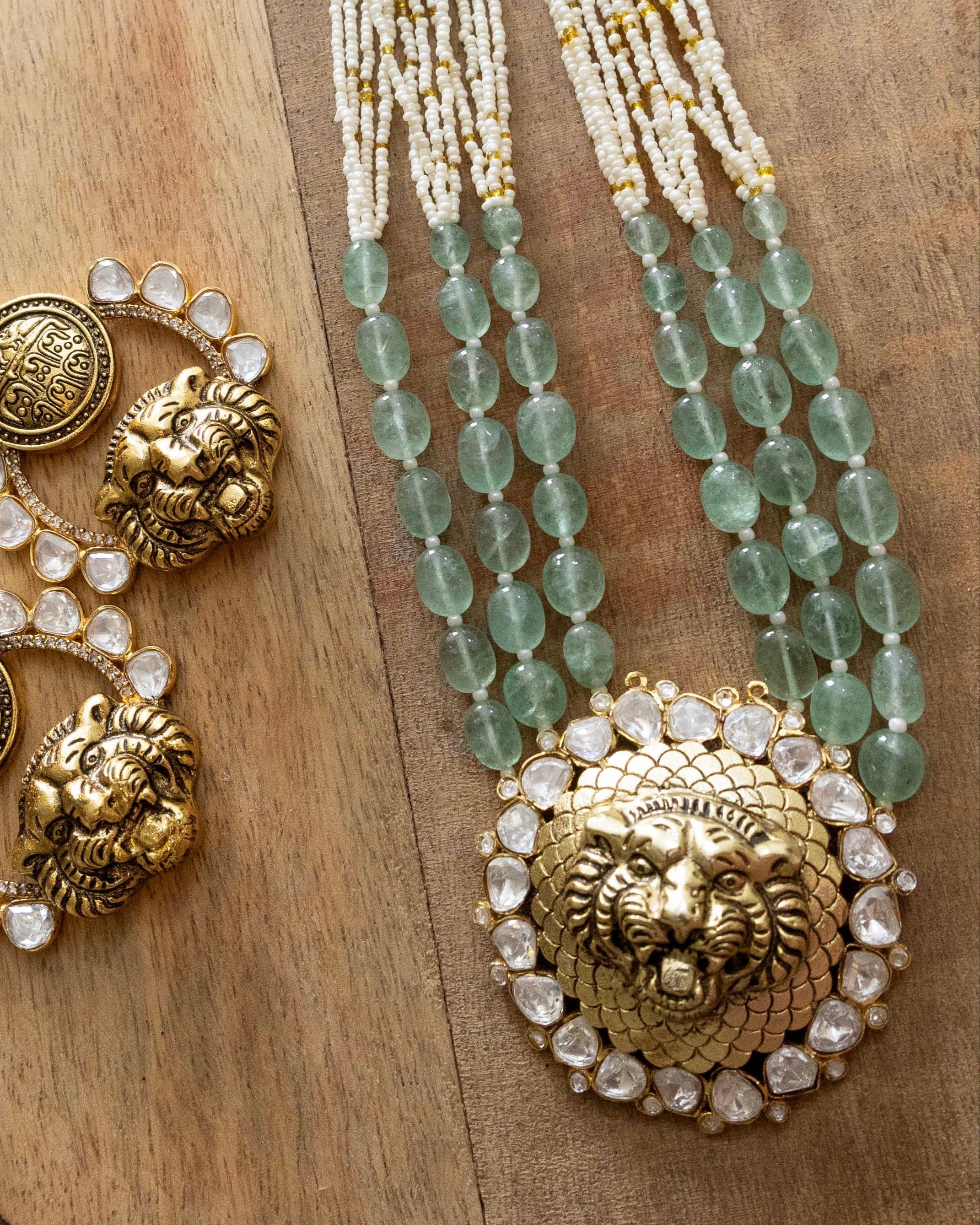 Flat lay of beaded kundan necklace set with lion motif pendant and matching earrings