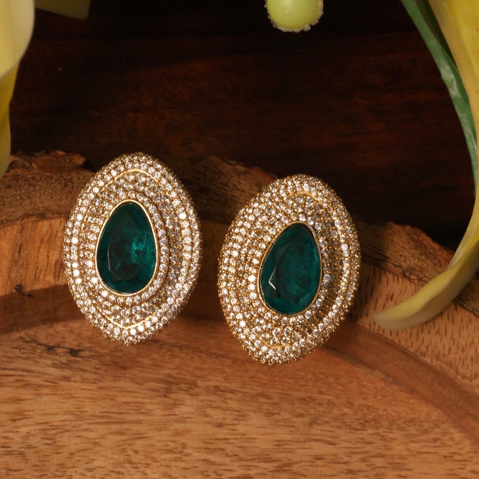 close-up of emerald-toned faux diamond earrings with gold plating and push-back clasp