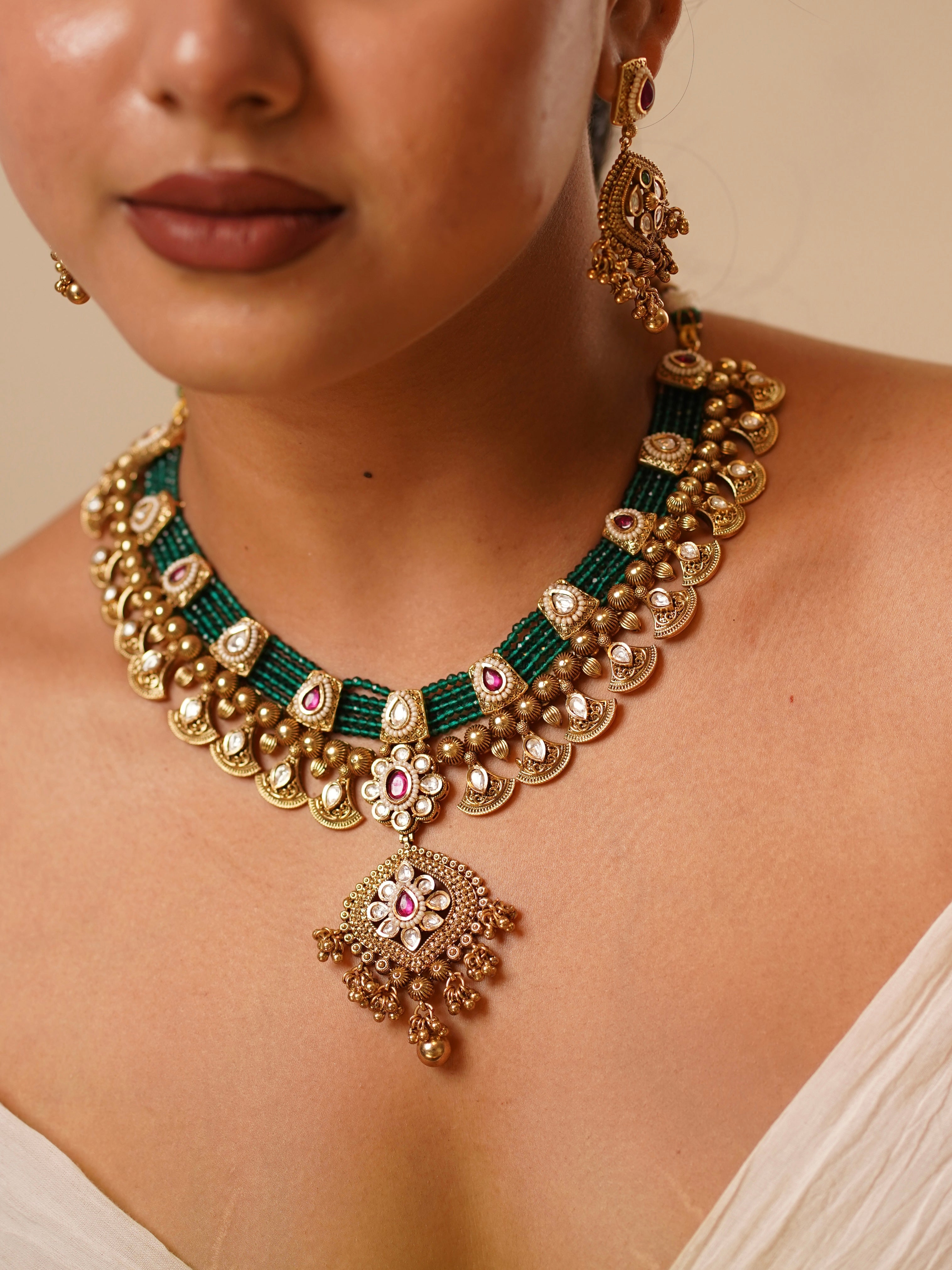 Emerald and ruby layered choker set with antique gold motifs and temple-inspired pendant