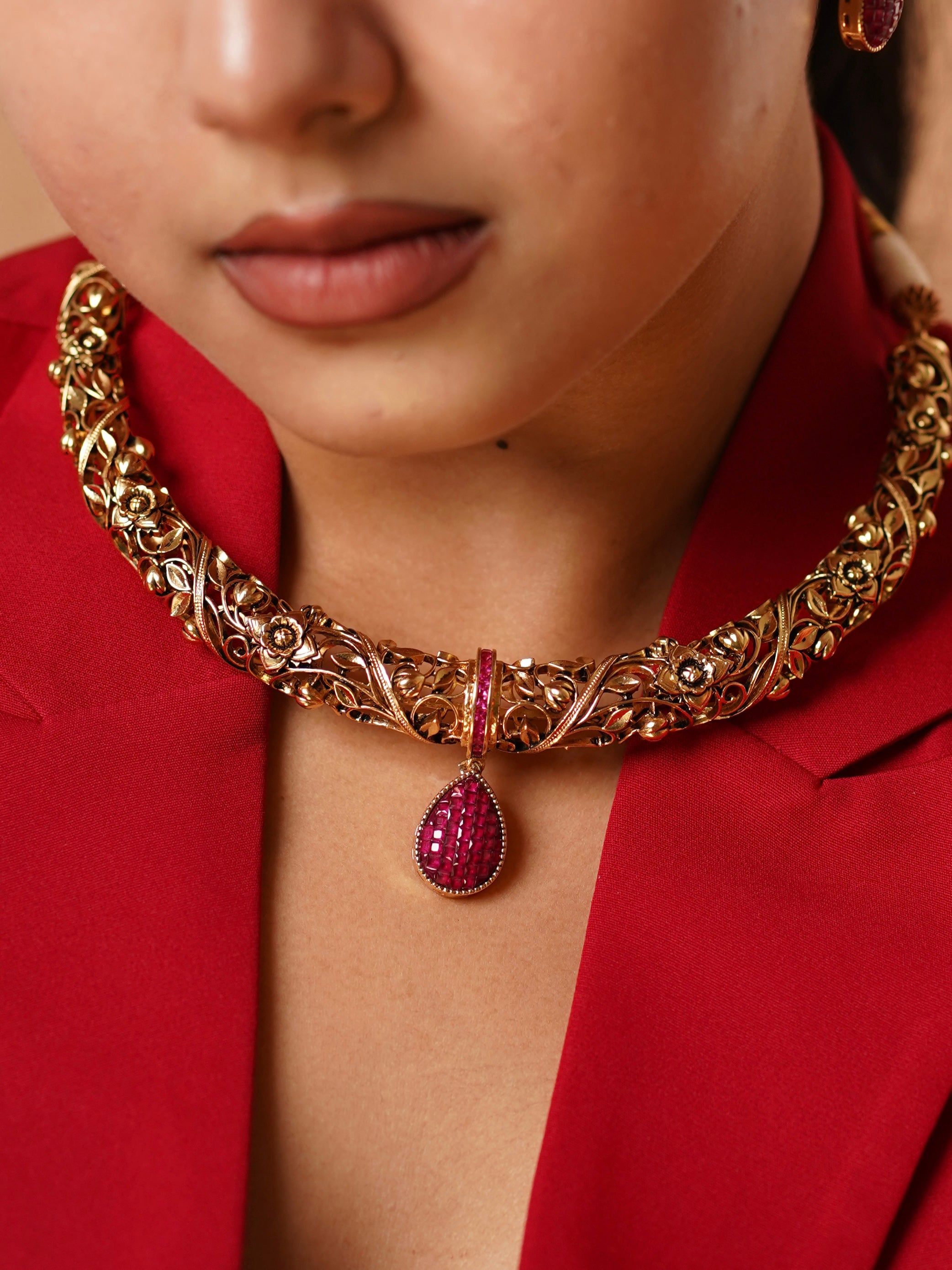 Close-up of necklace pendant with ruby detailing and intricate gold craftsmanship