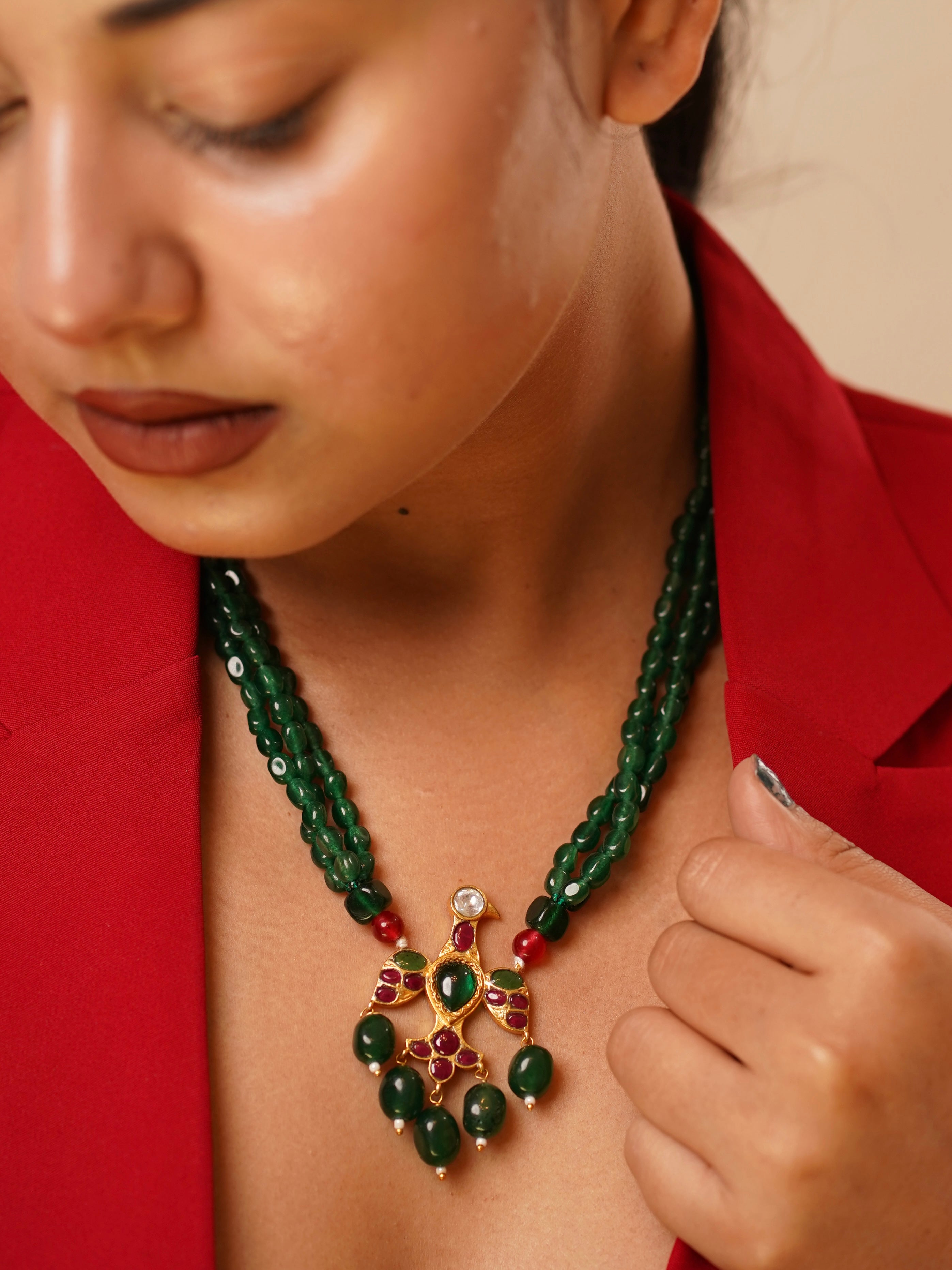 Close-up of eagle pendant necklace with ruby accents and gold-plated finish