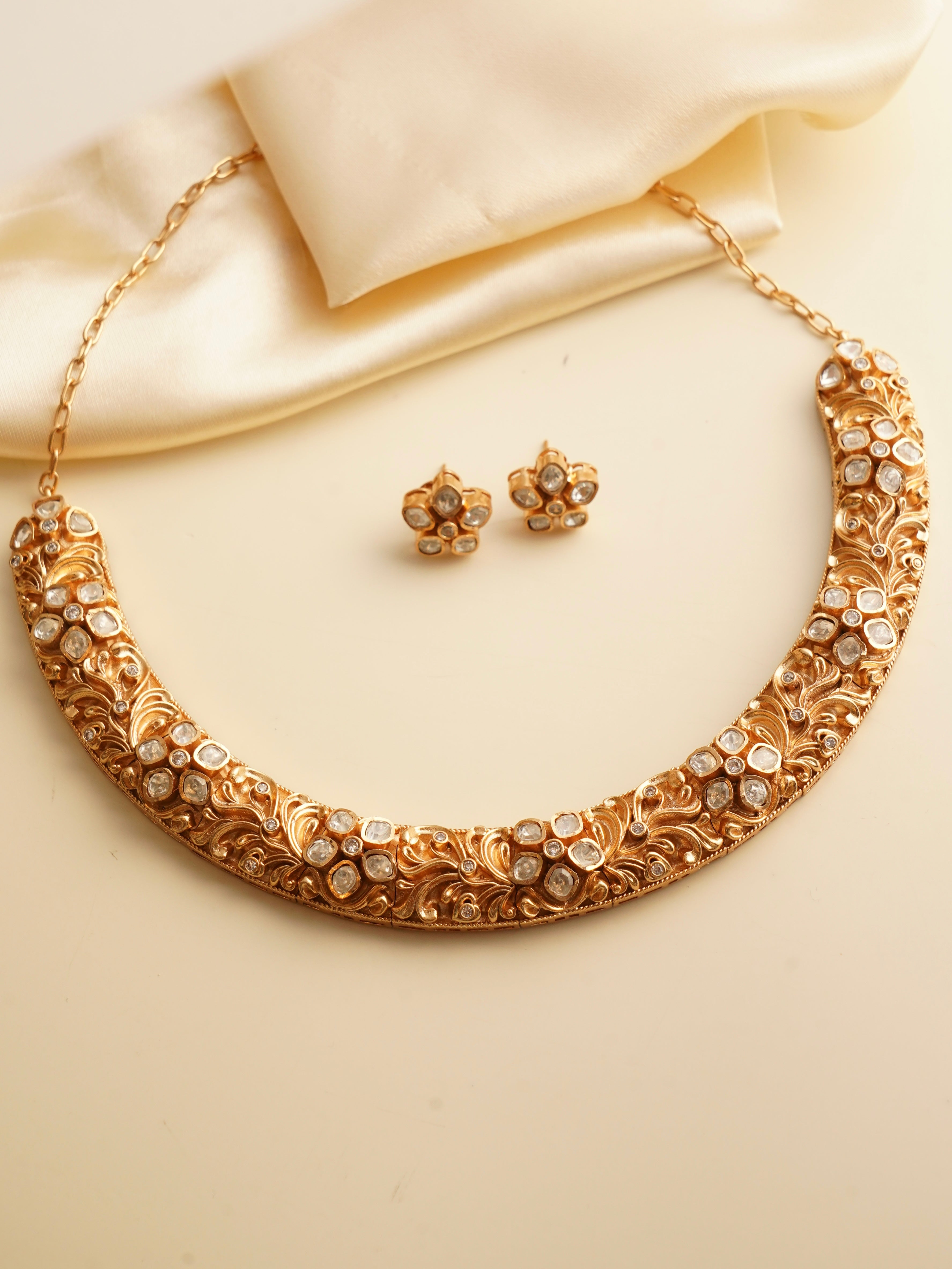 Side angle of gold-tone polki hasli set with floral polki studs and engraved hasli