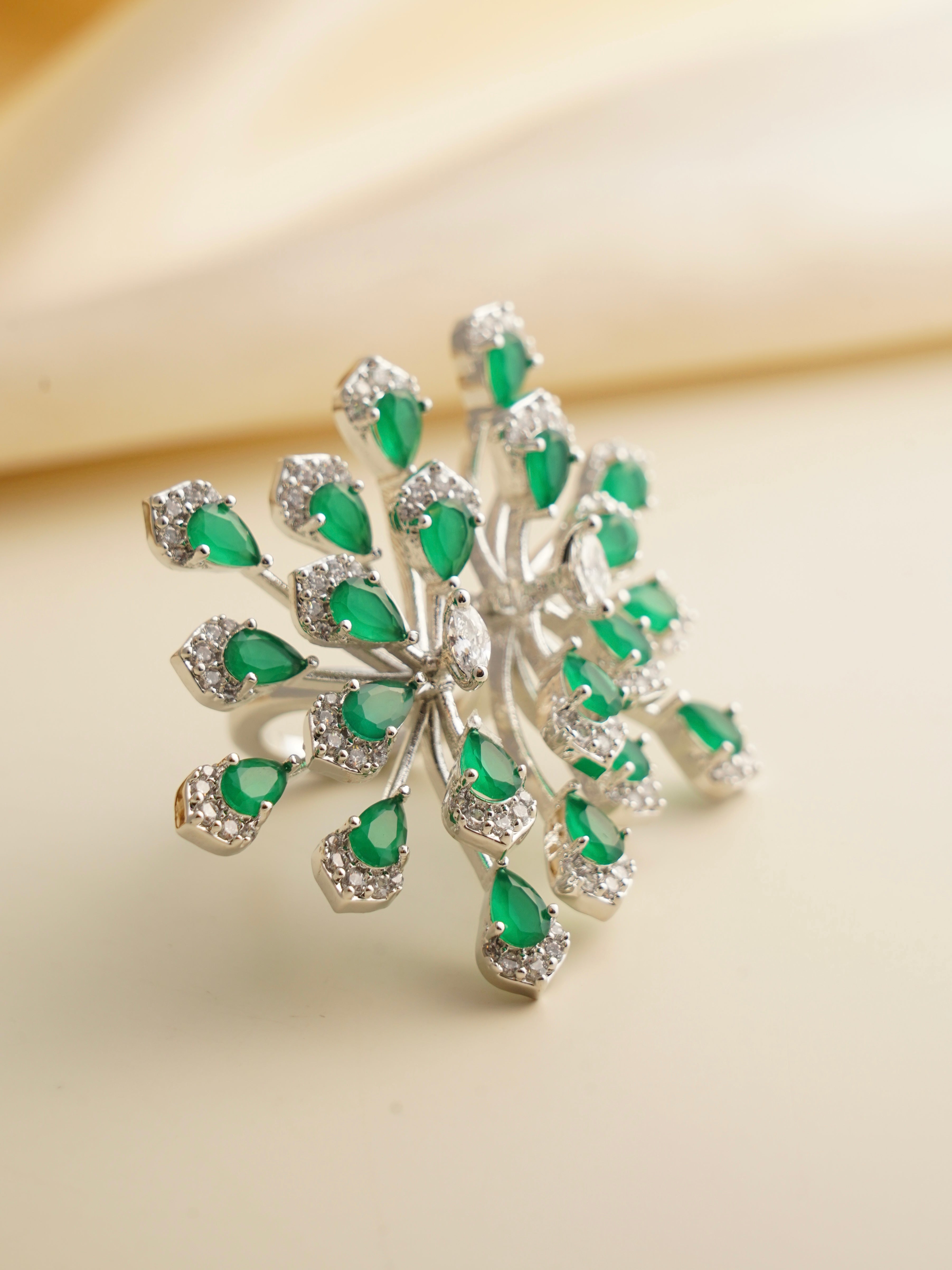 Front view of emerald burst cocktail ring with teardrop stones and shimmering accents