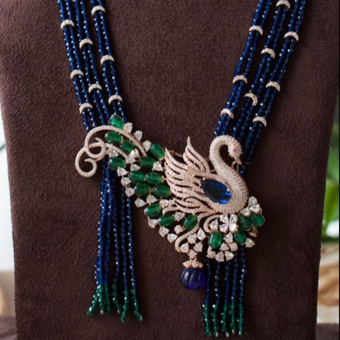 front view of bird-inspired necklace with beaded strands and matching peacock earrings