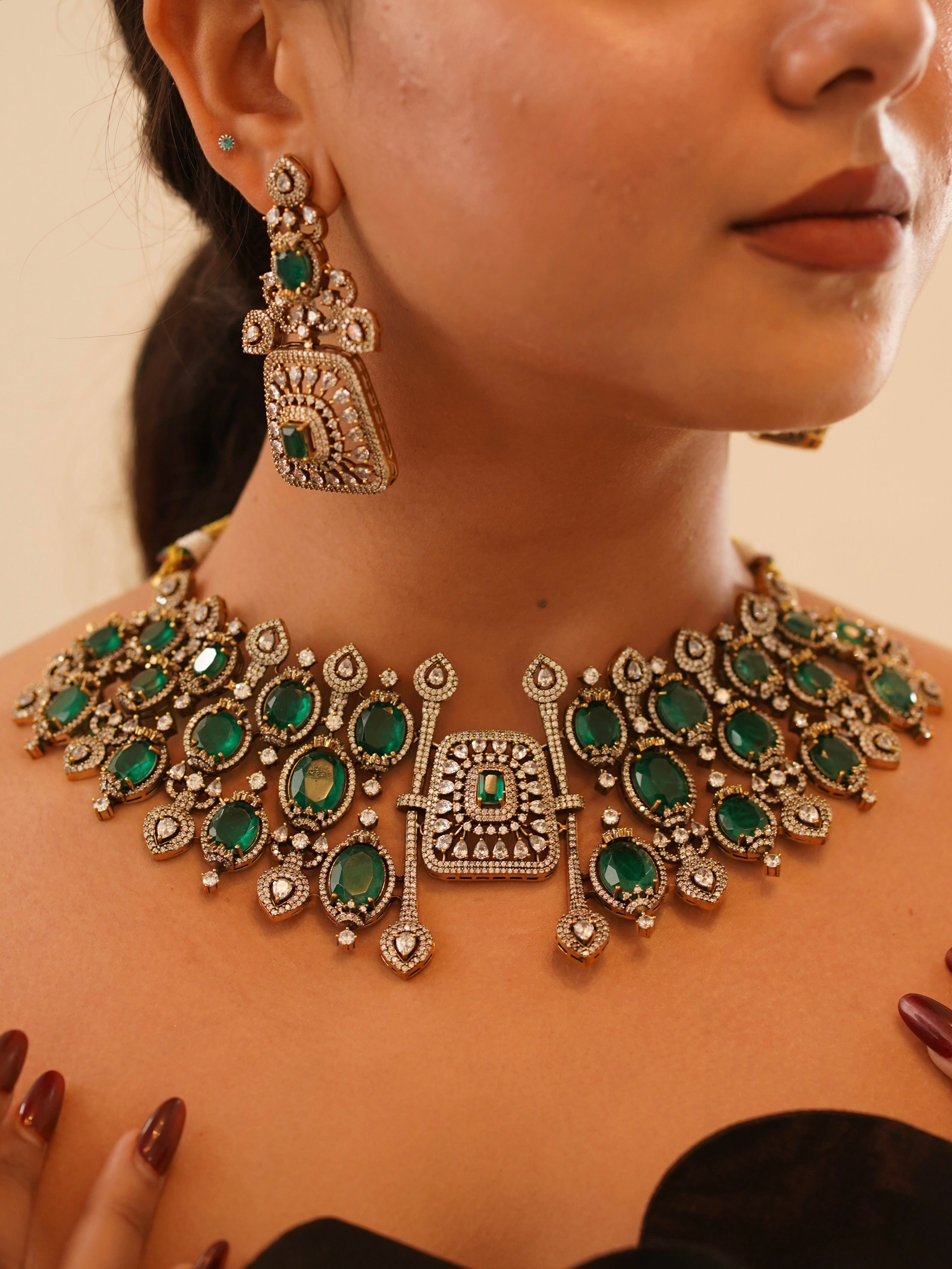 Side view of ruby green choker set with kundan detailing and gemstone-studded earrings