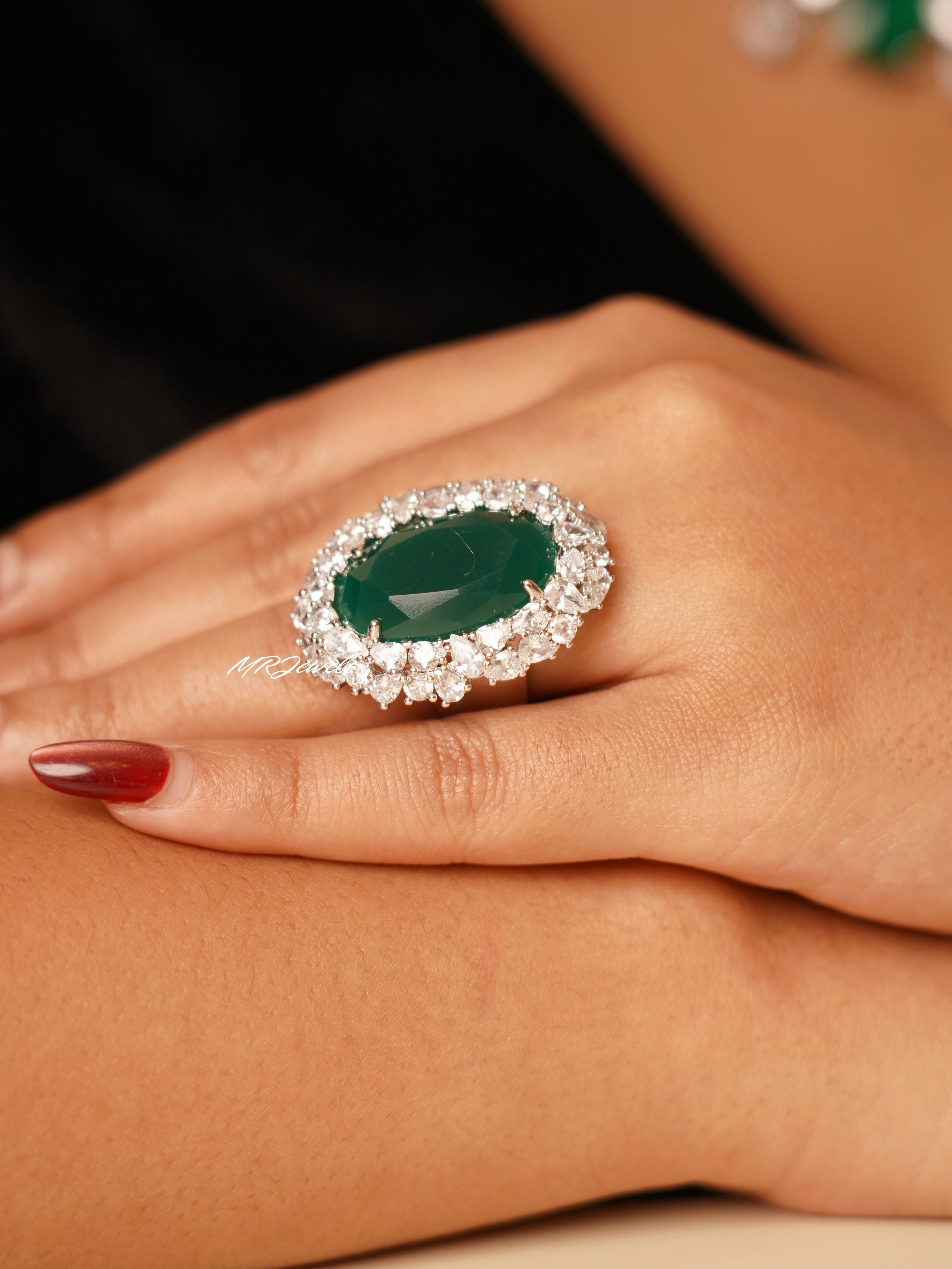 Regal emerald radiance ring with central green stone surrounded by halo of shimmering CZ crystals