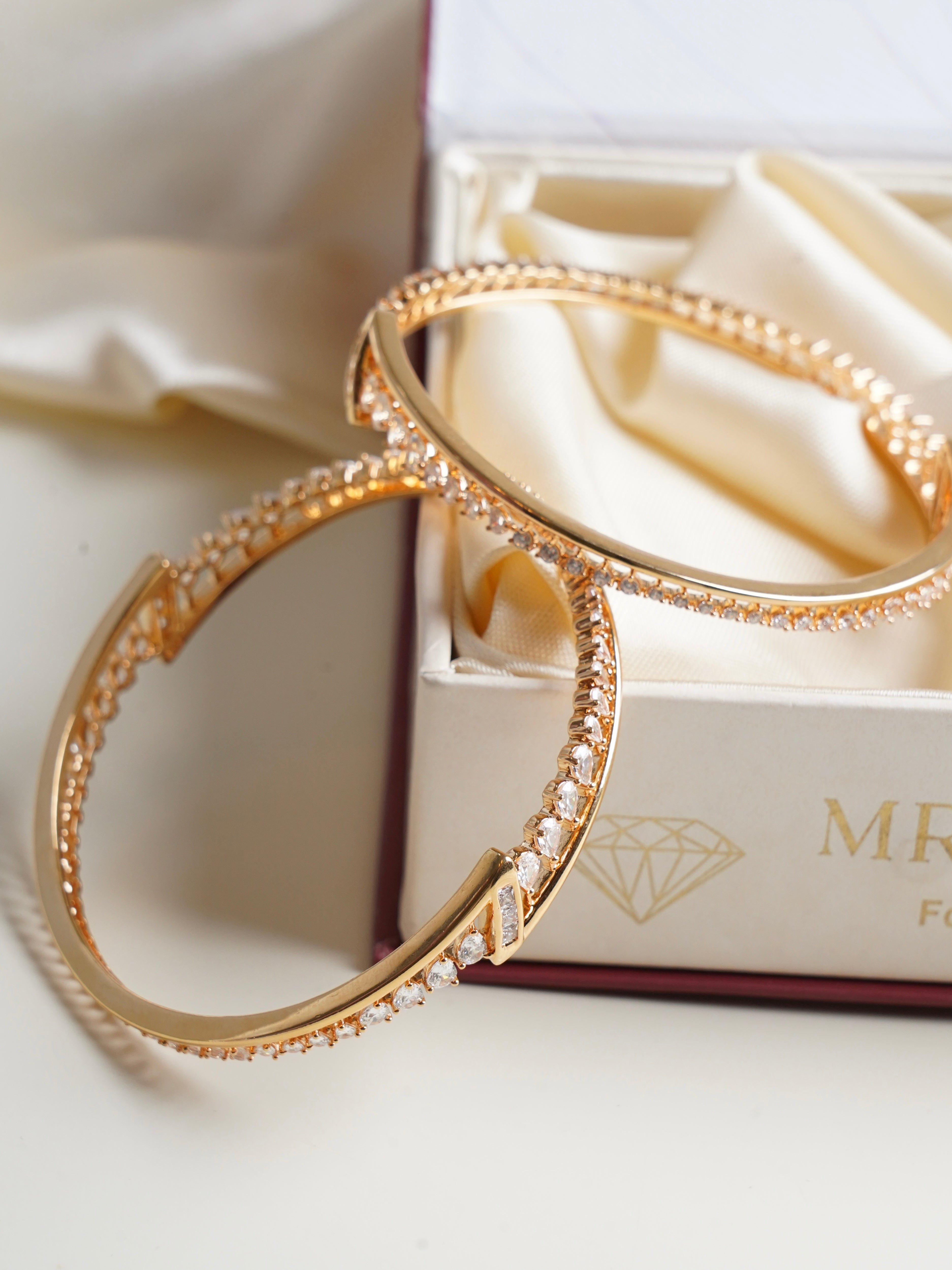 Gold-finish bangles featuring intricate diamond cutwork and sleek contemporary styling