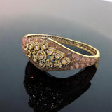 Close-up of openable gold bracelet featuring ruby, emerald, and champagne enamel