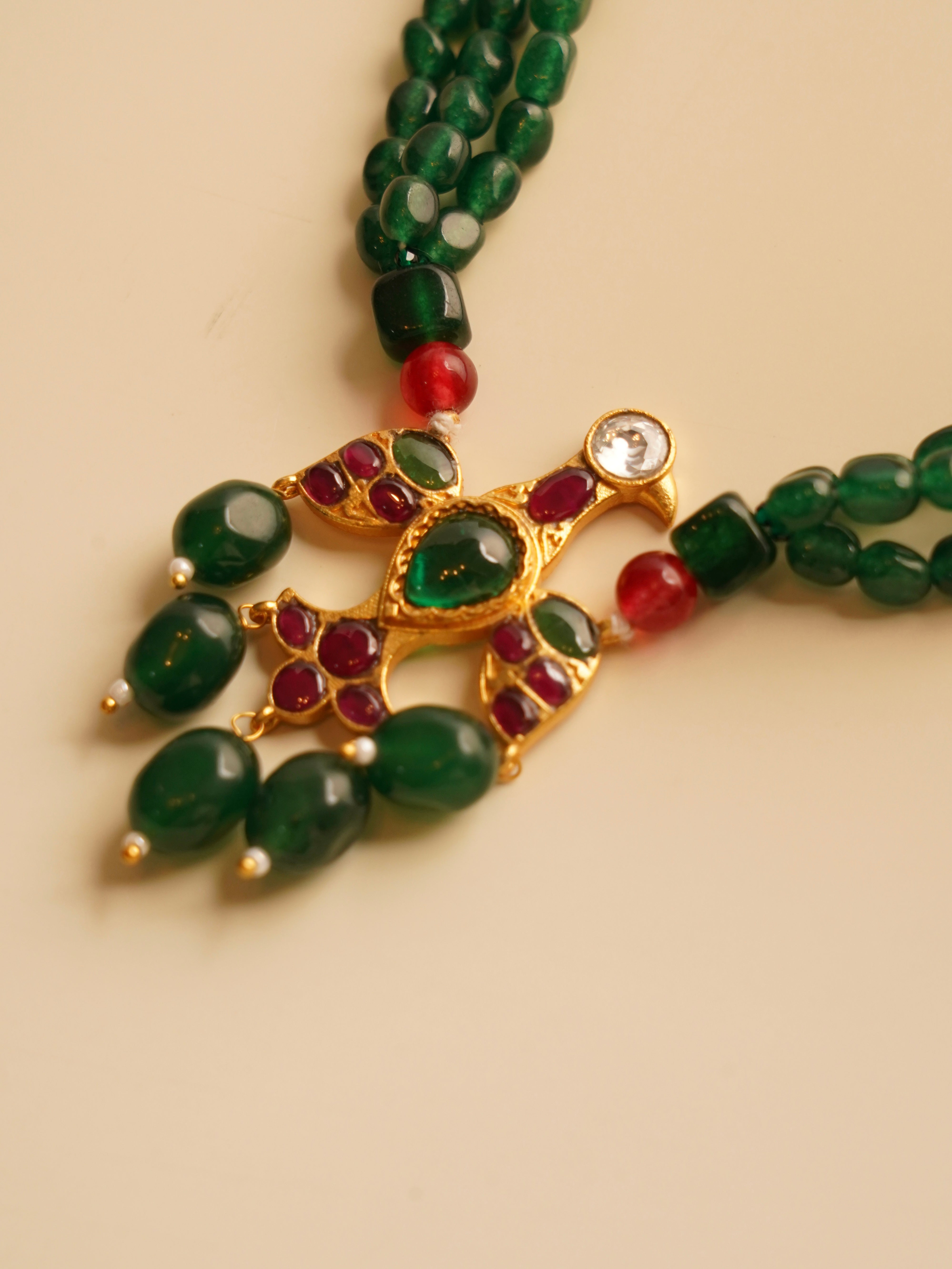 Side angle of emerald beaded necklace with eagle motif and kundan embellishments