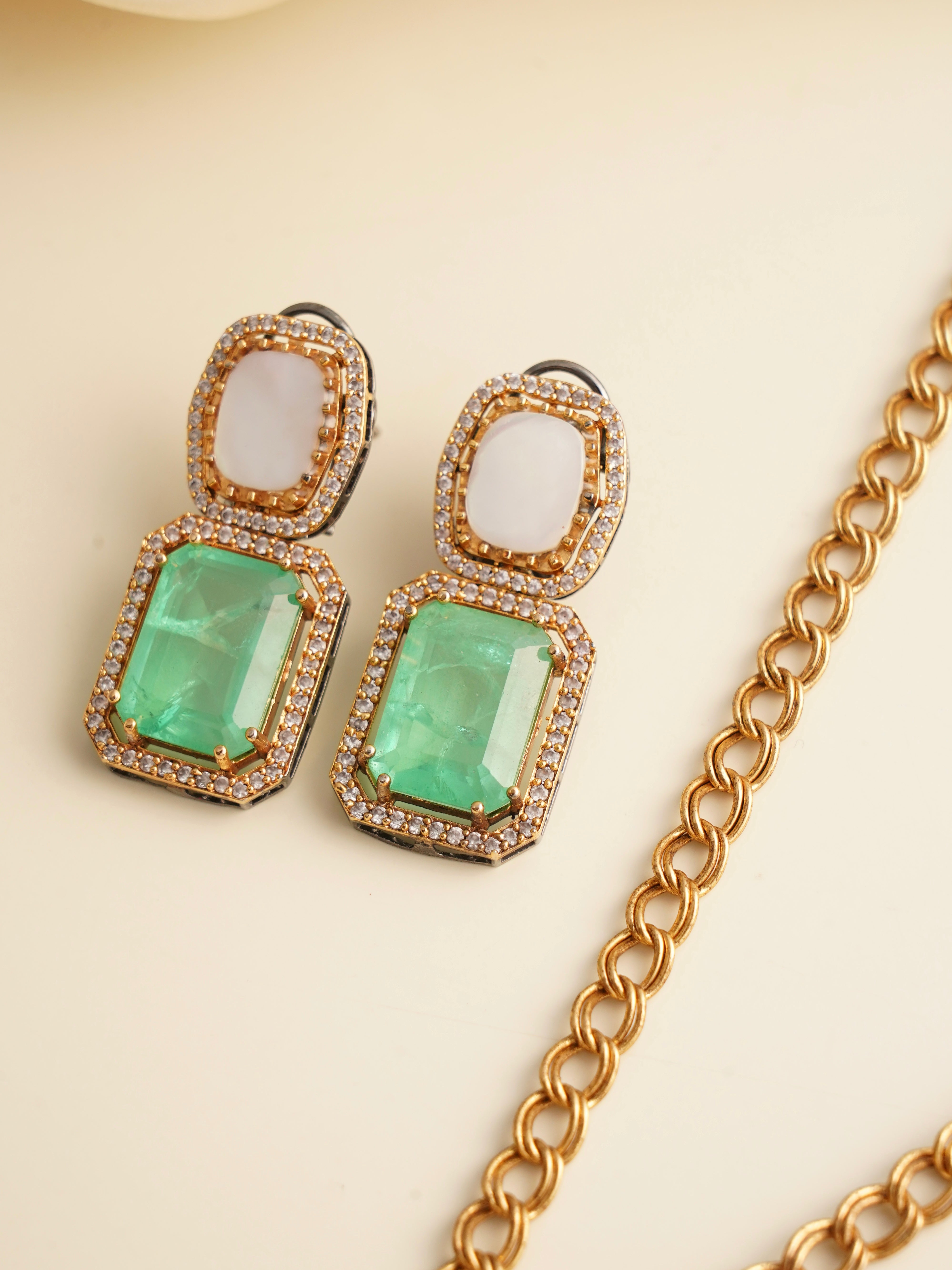 Angled view of pendant and earrings from emerald radiance set with detailed stonework