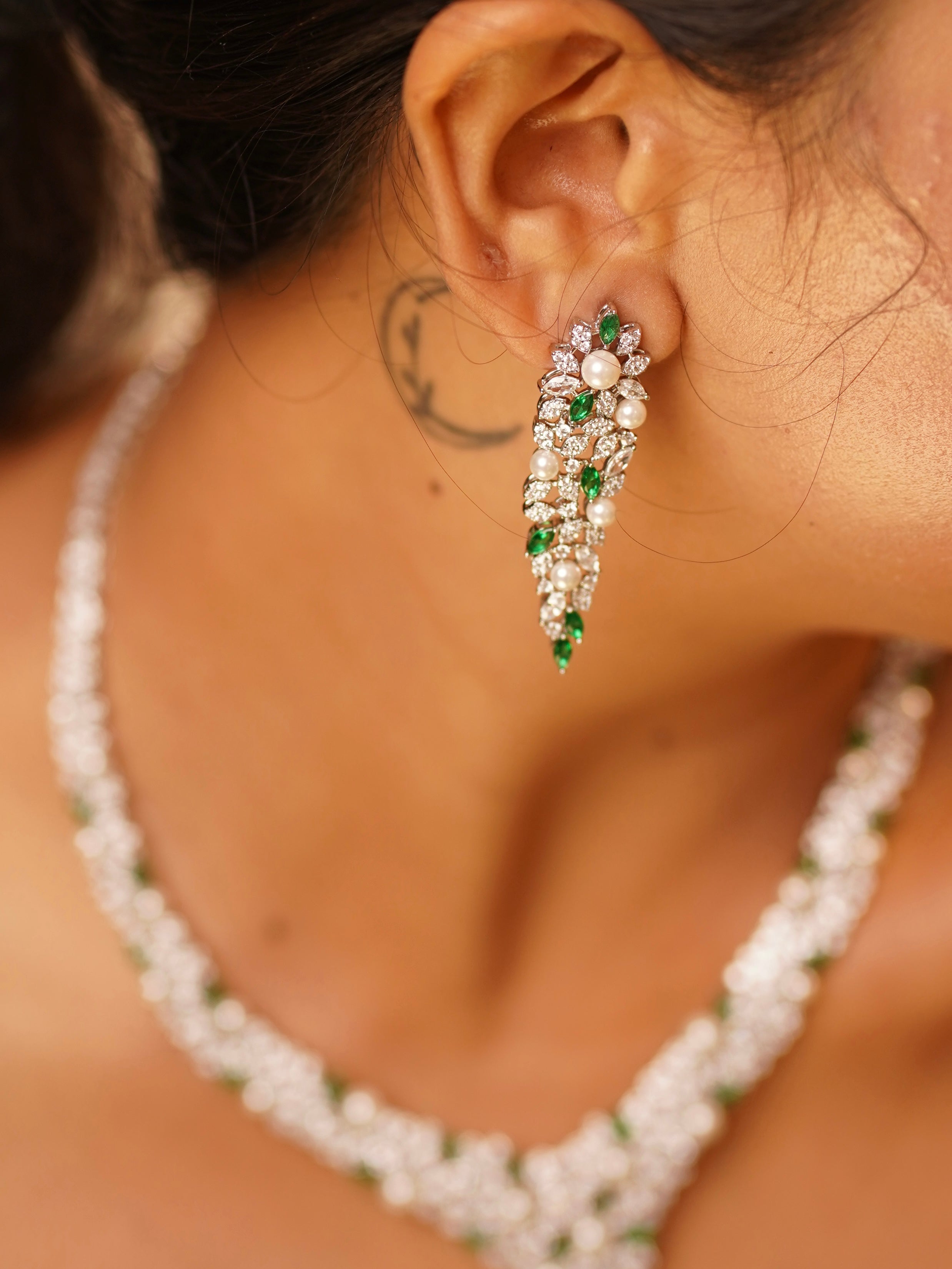 Close-up of emerald diamond necklace with matching earrings and natural pearl accents