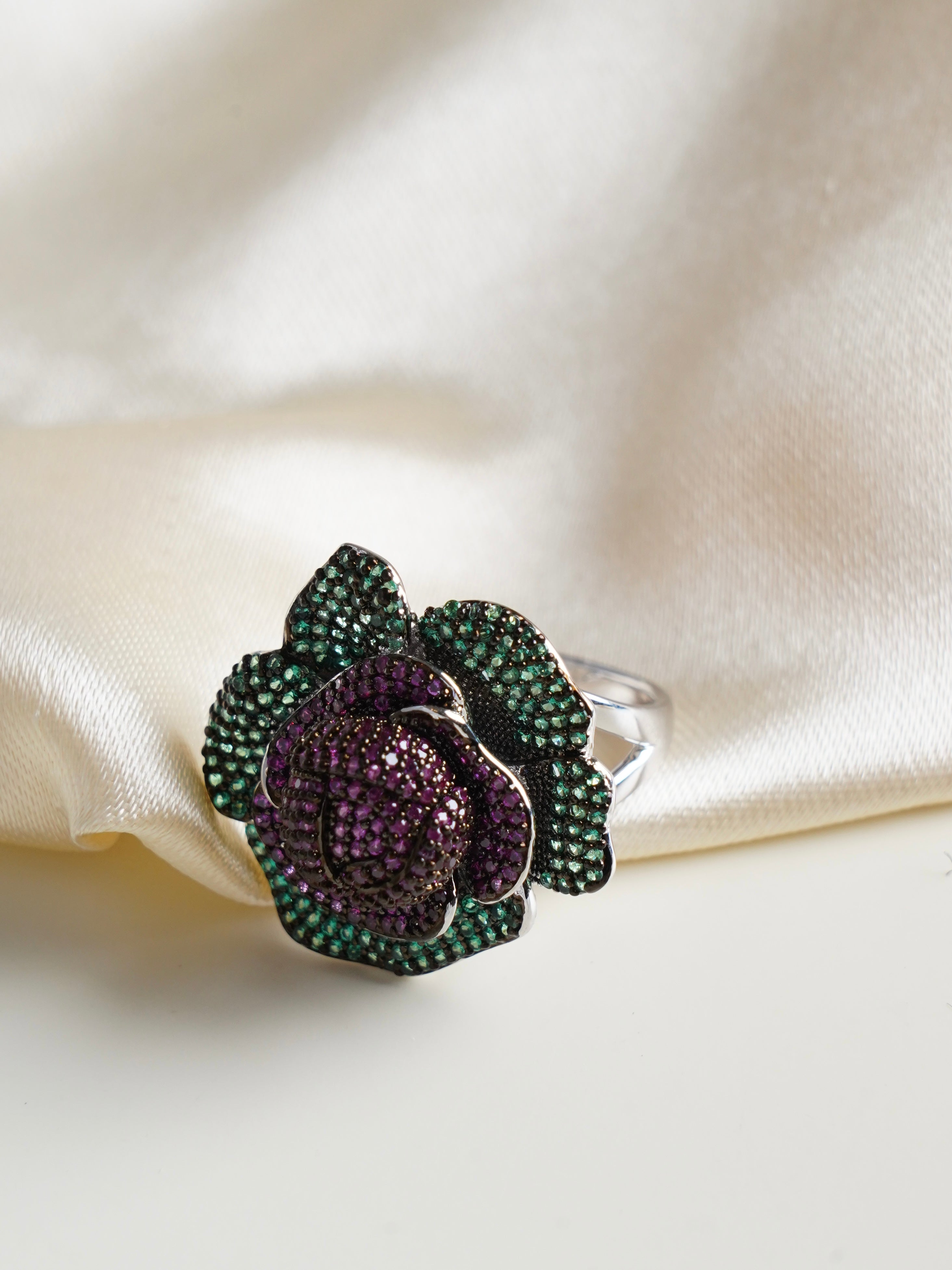Side view of blooming rose ring showing handcrafted petal curves with purple and green stone contrast