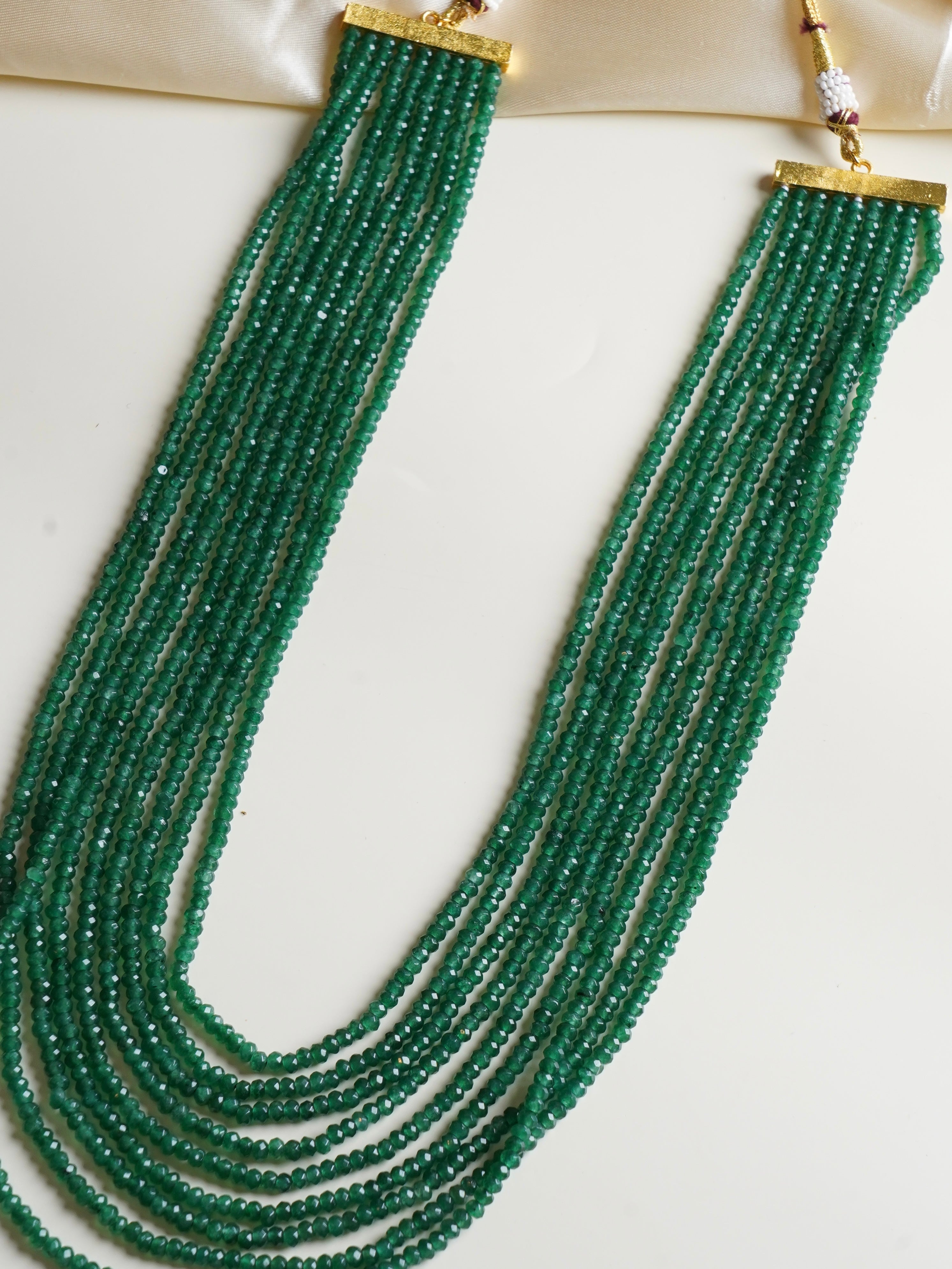 Multi-strand necklace with faceted gemstone beads in vibrant ruby, emerald, and sapphire tones