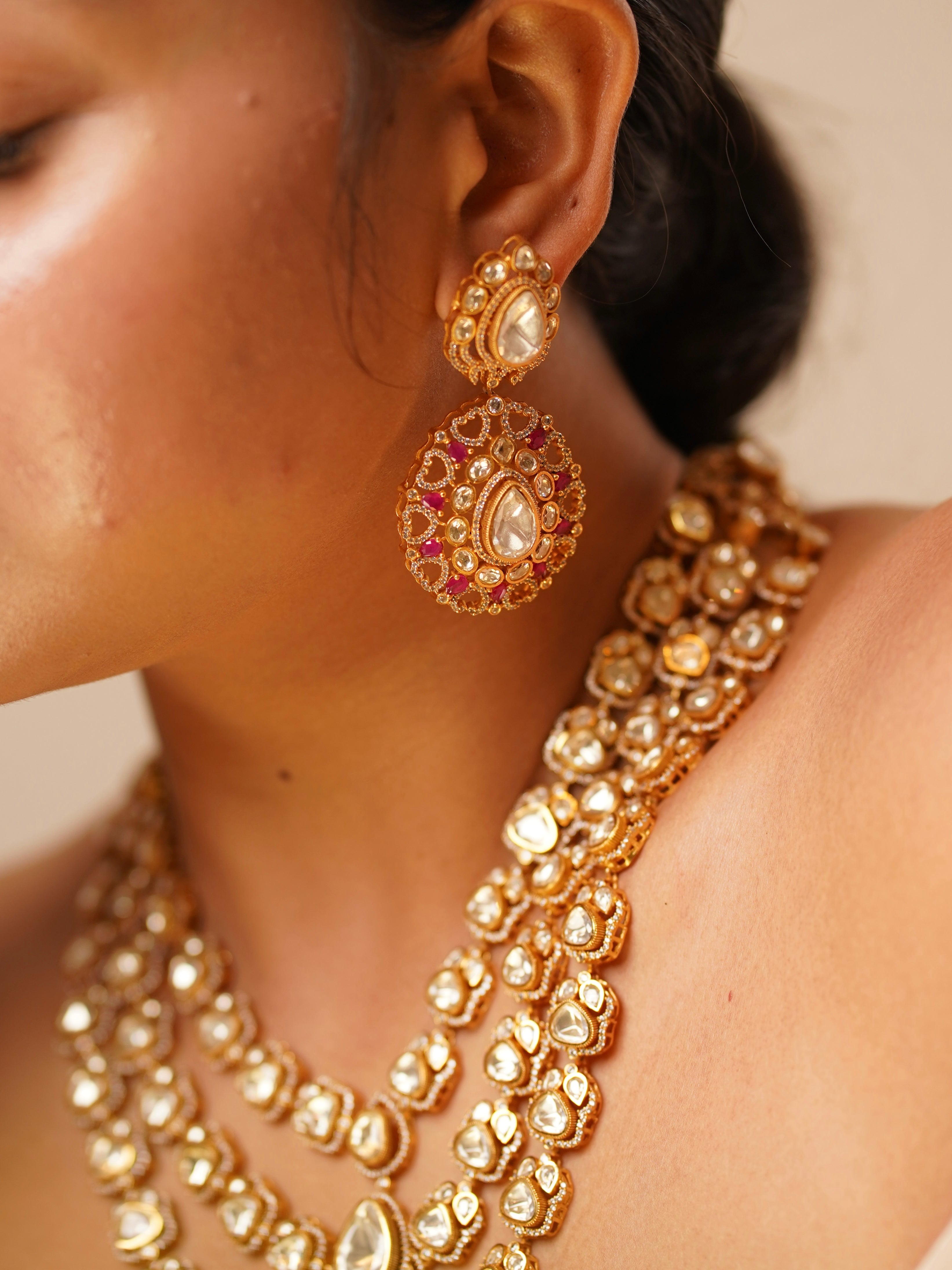 Close-up of ruby-accented moissanite bridal necklace set with intricate layered design