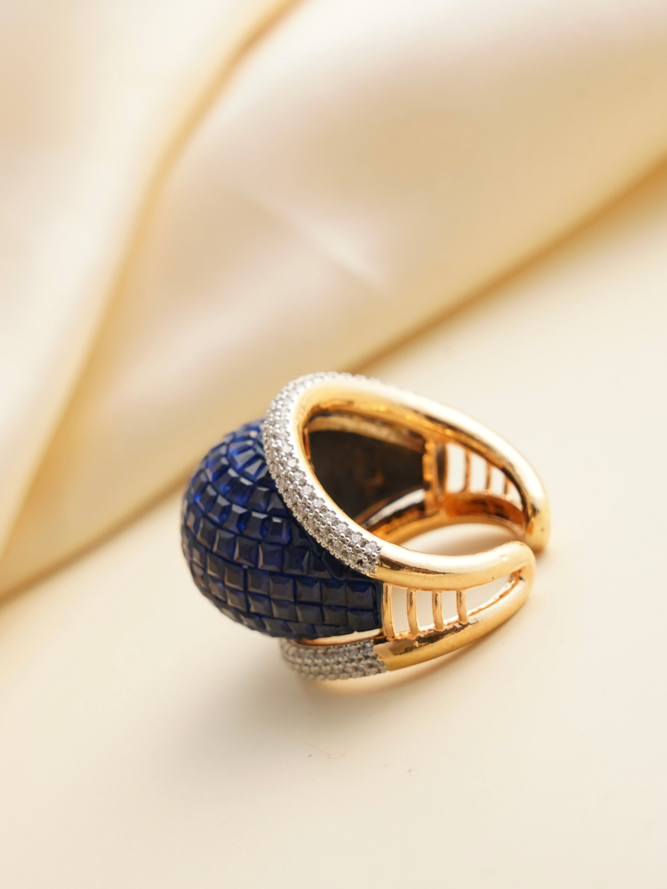 Angled view of adjustable deep blue gemstone ring with gold finish and diamond accents