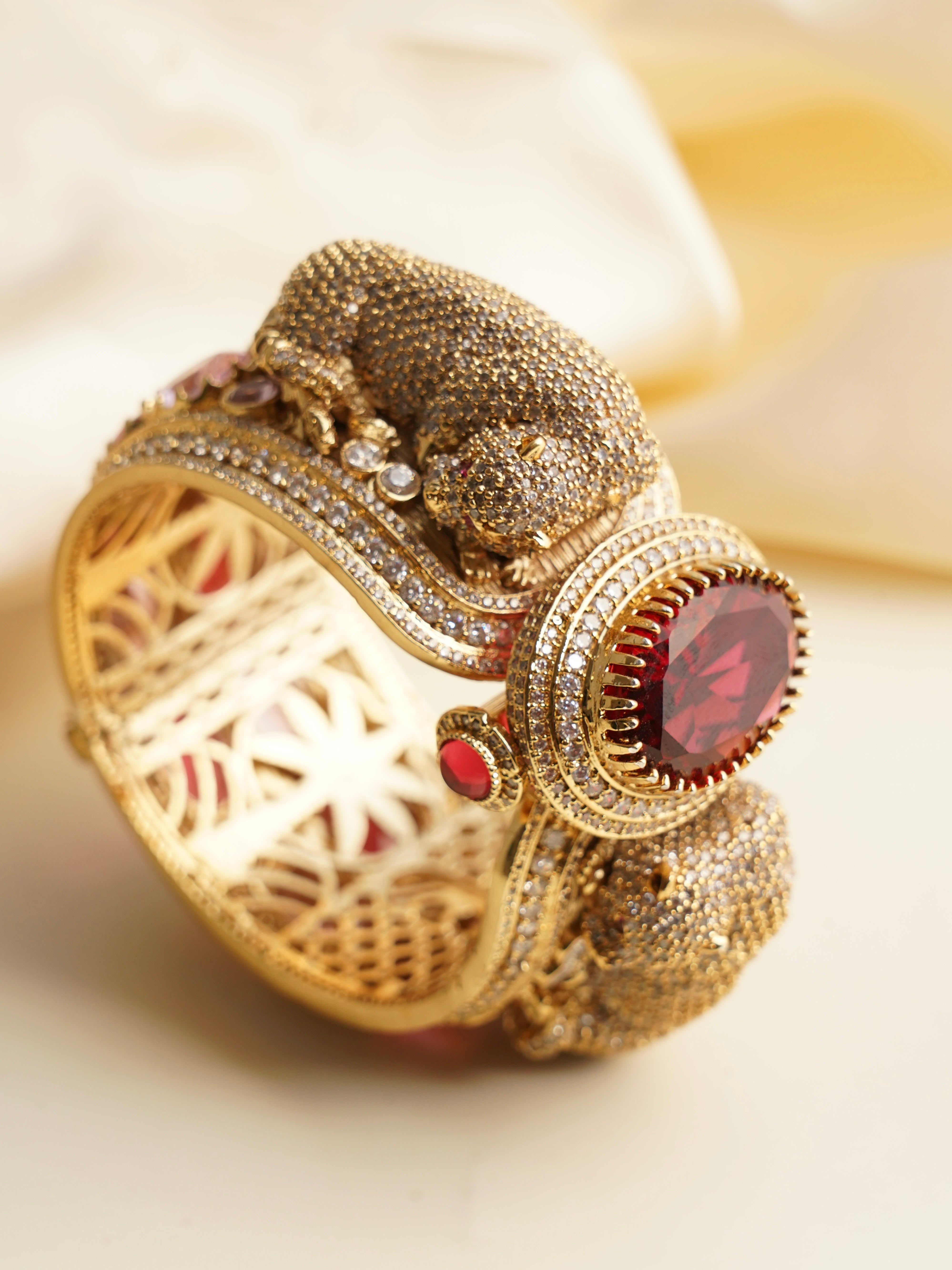 Panther-themed gold bangle with twin micro zircon encrusted heads and ruby-toned center stone