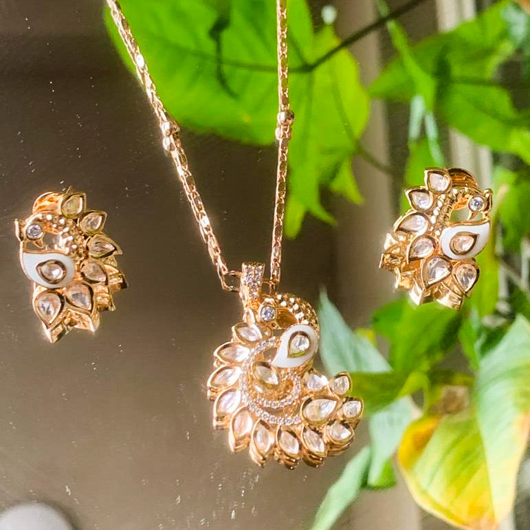 Angled view of kundan peacock pendant with matching drop earrings