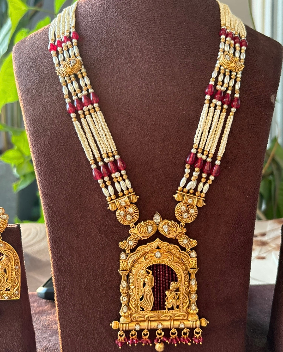 Front view of Radha Krishna necklace set showing ruby and pearl embellishments with pendant