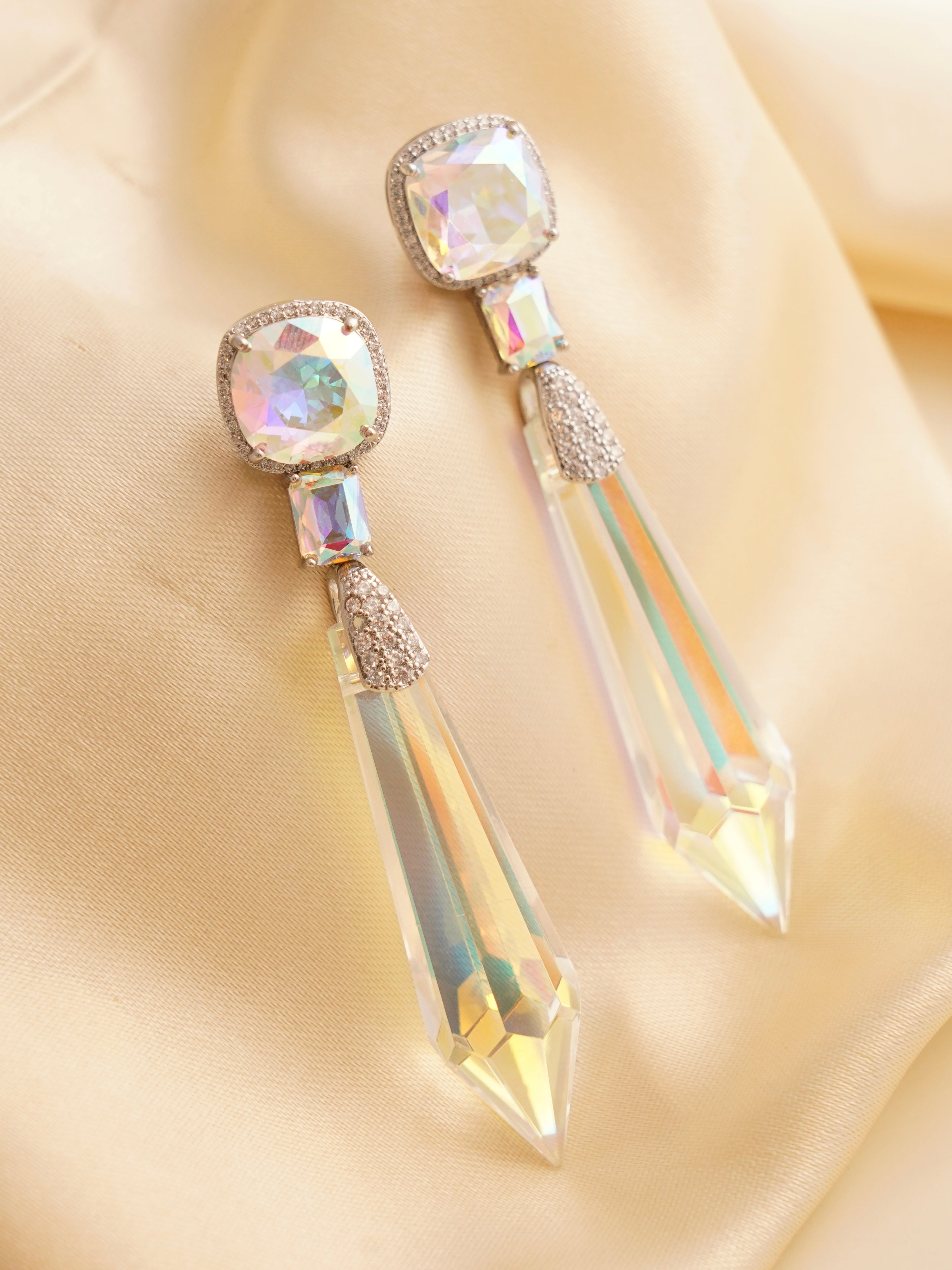 Close-up of crystal earrings showing faceted drops in bold hues with sparkling CZ detail