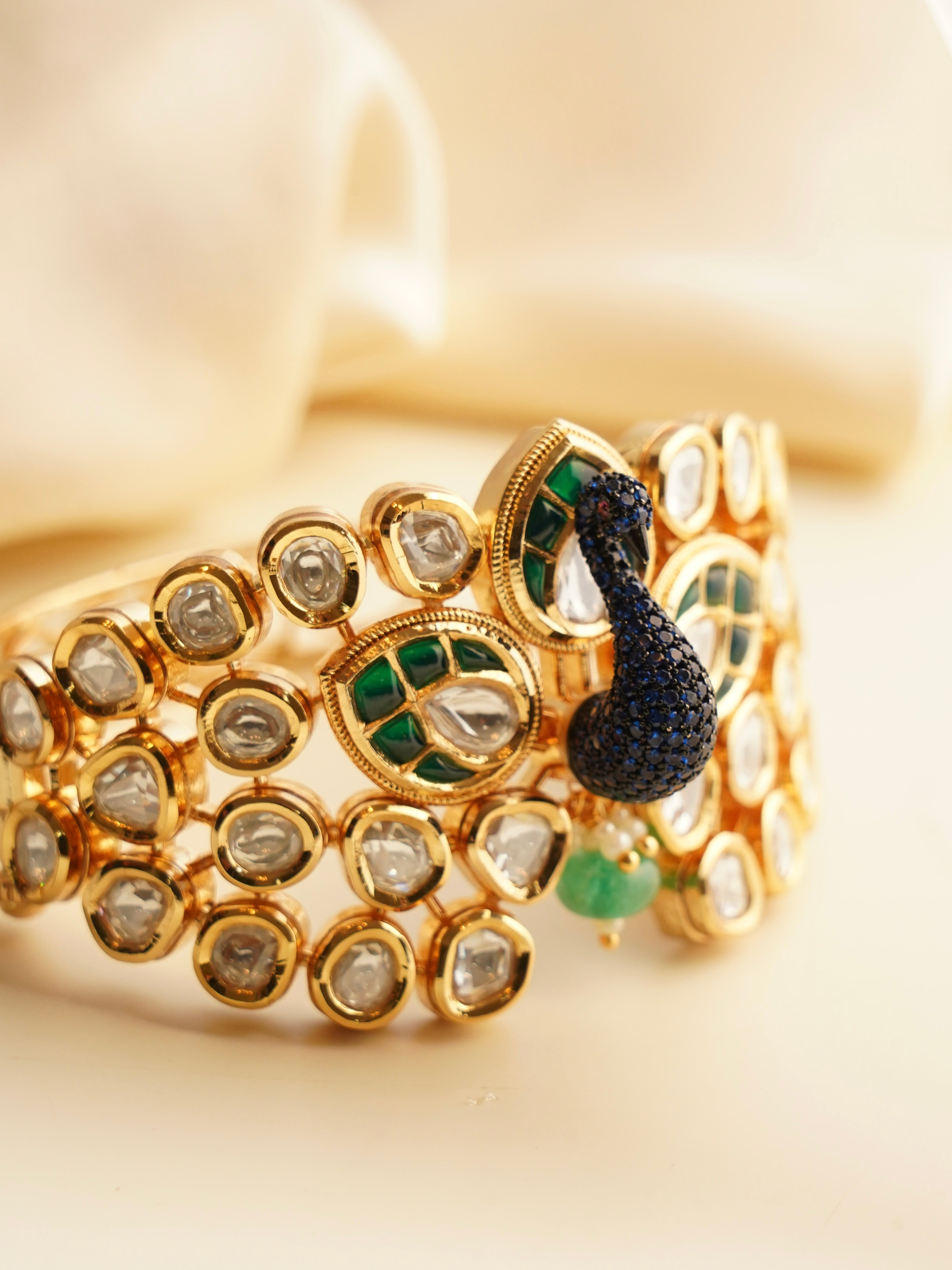 peacock-inspired bracelet with gold finish and sparkling diamond accents