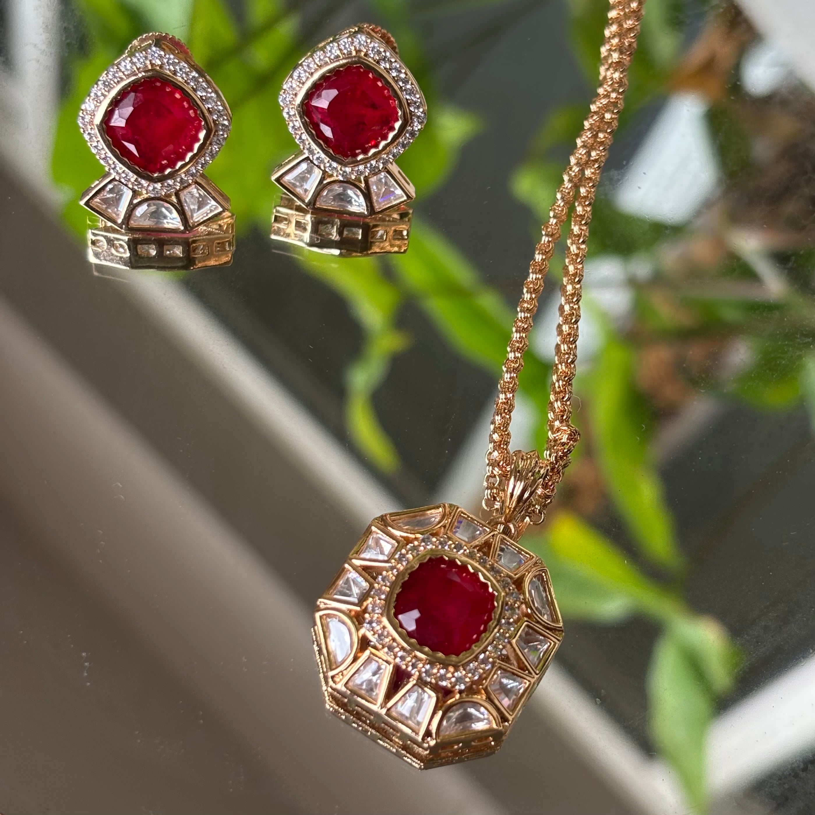 Front view of red stone pendant set with micron gold detailing and matching earrings