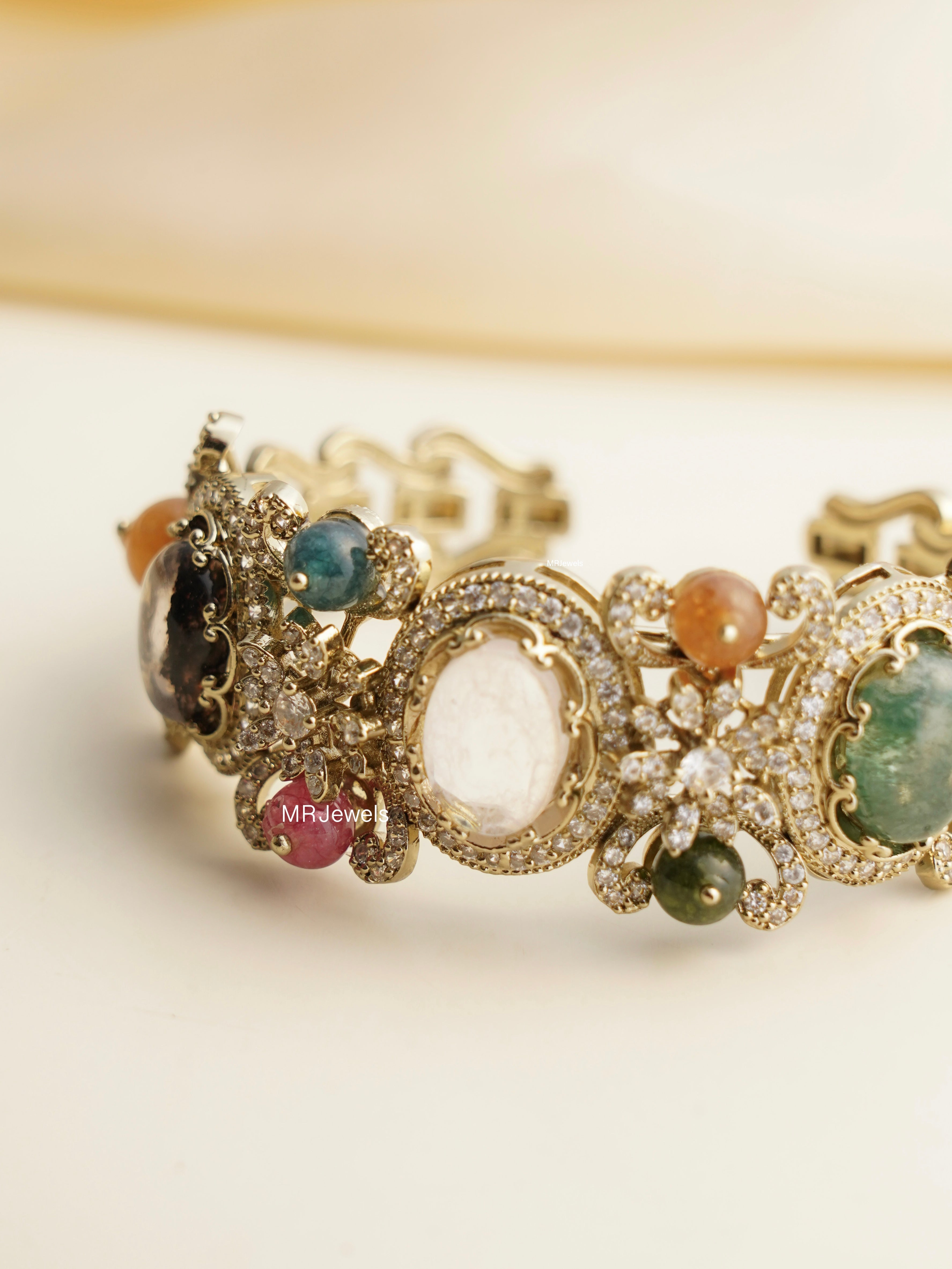 Angled view of gold navratna kada with meenakari detailing and traditional gemstone arrangement