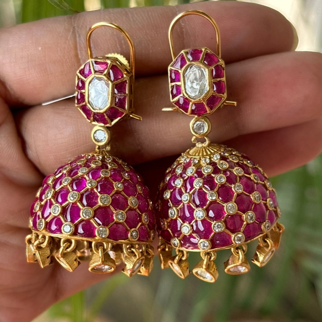 Gold-finish jhumka earrings with turquoise stones and polki diamonds in angled view