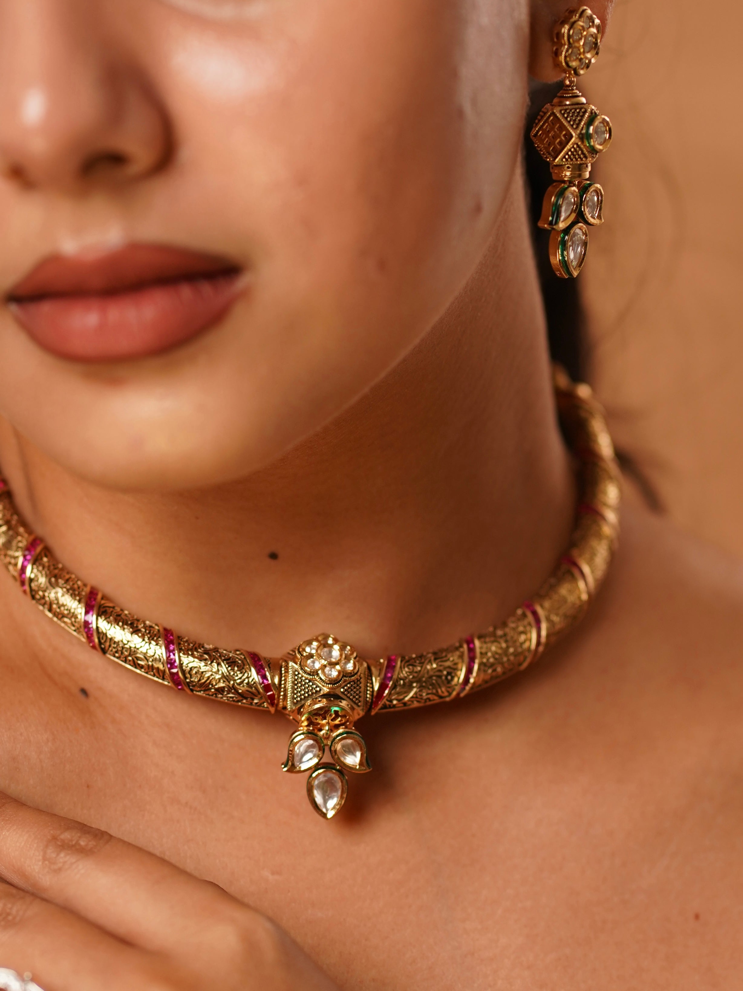 Angled image of vilandi hasli necklace featuring ruby stones and curved neckband form