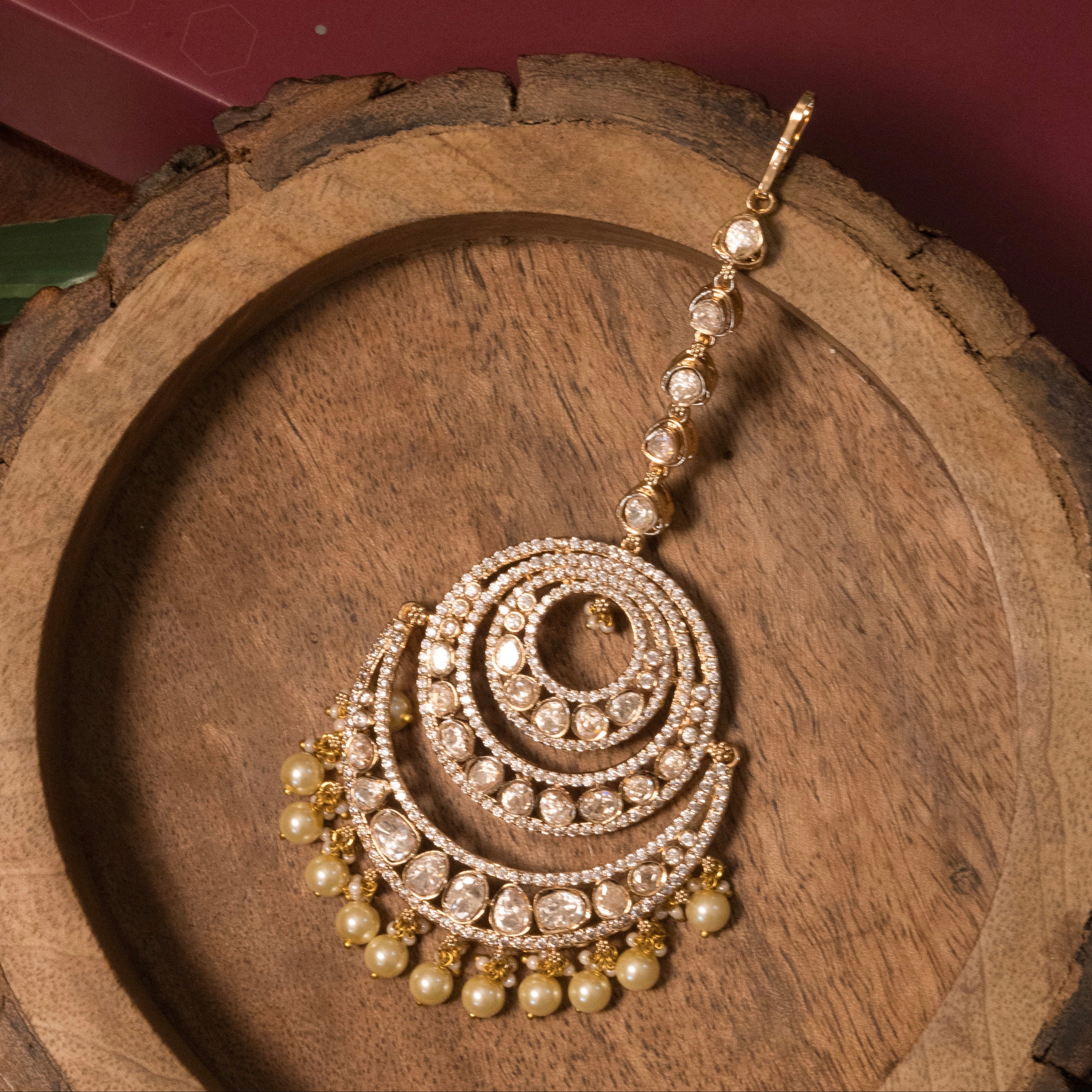 Crescent mangtikka with moissanite stones and pearl details, styled against white background
