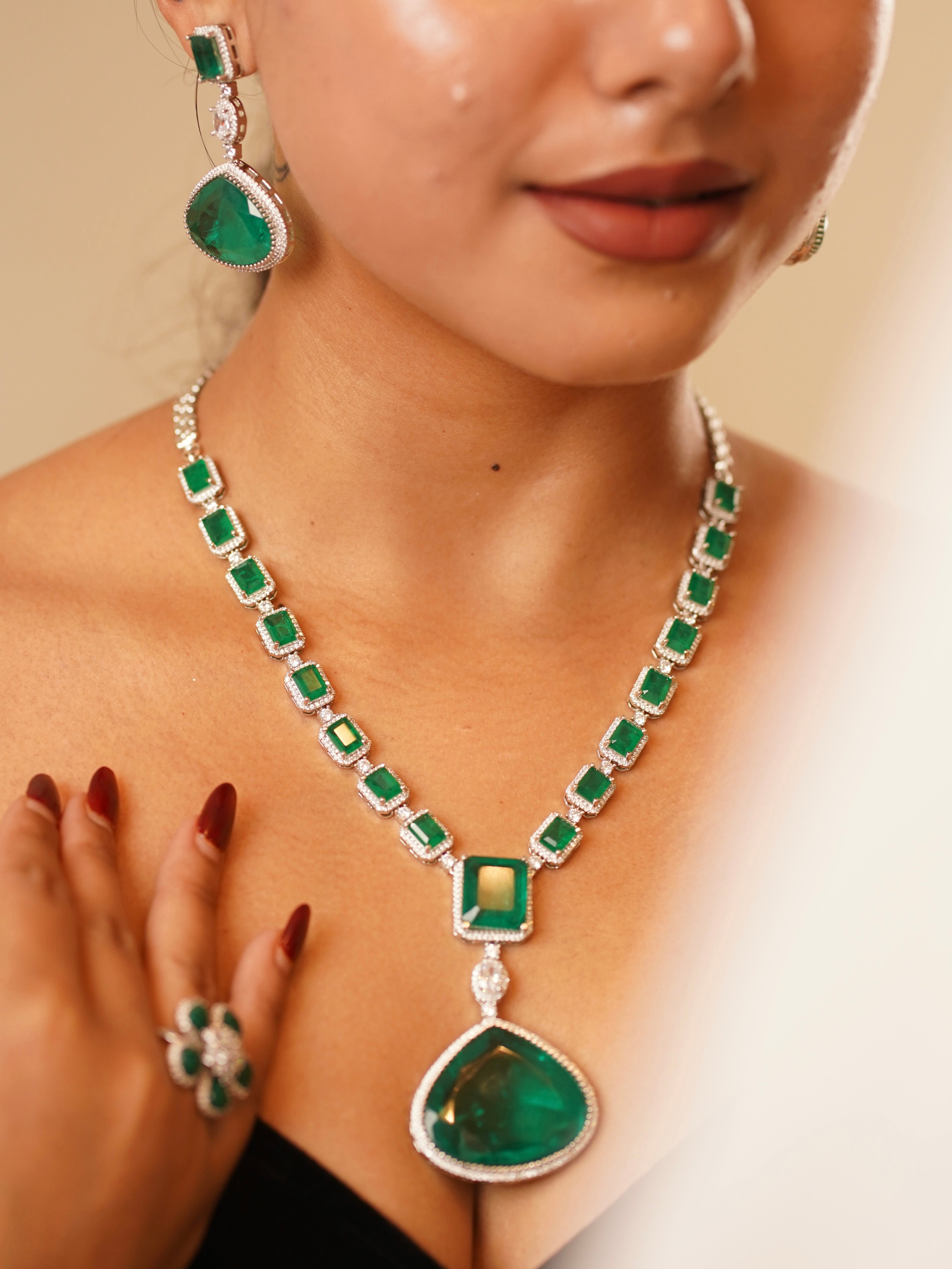 Side view of emerald necklace with crystal halo settings and matching drop earrings