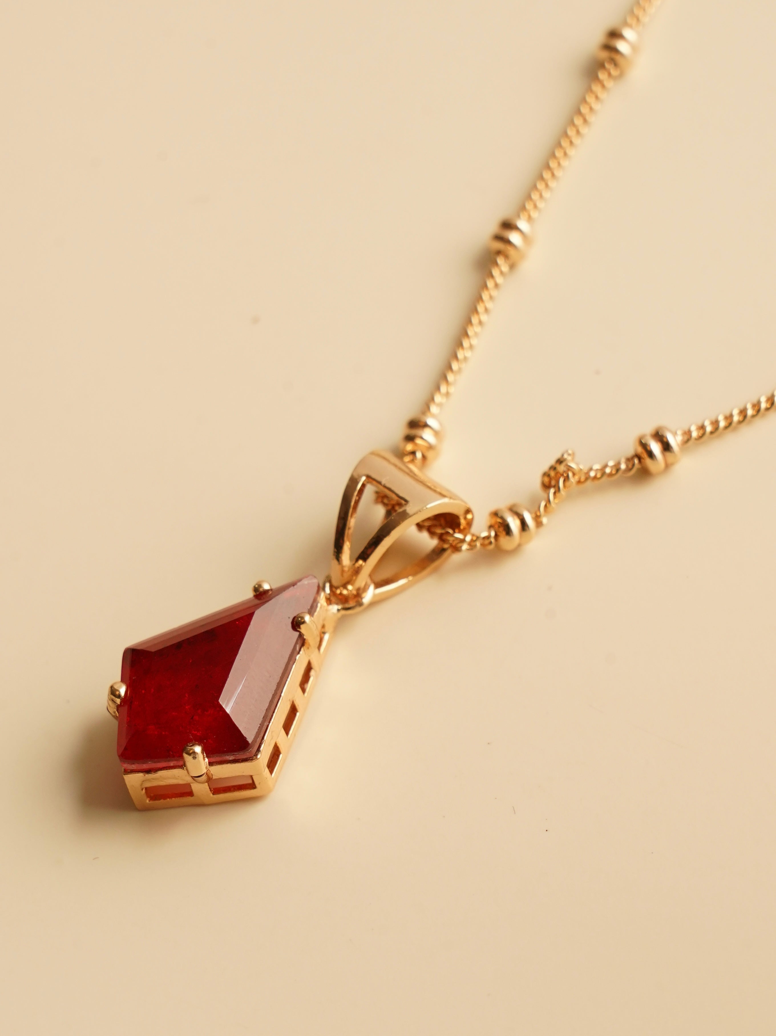 Side view of emerald prism pendant and earrings showing faceted cut and gold-toned frame