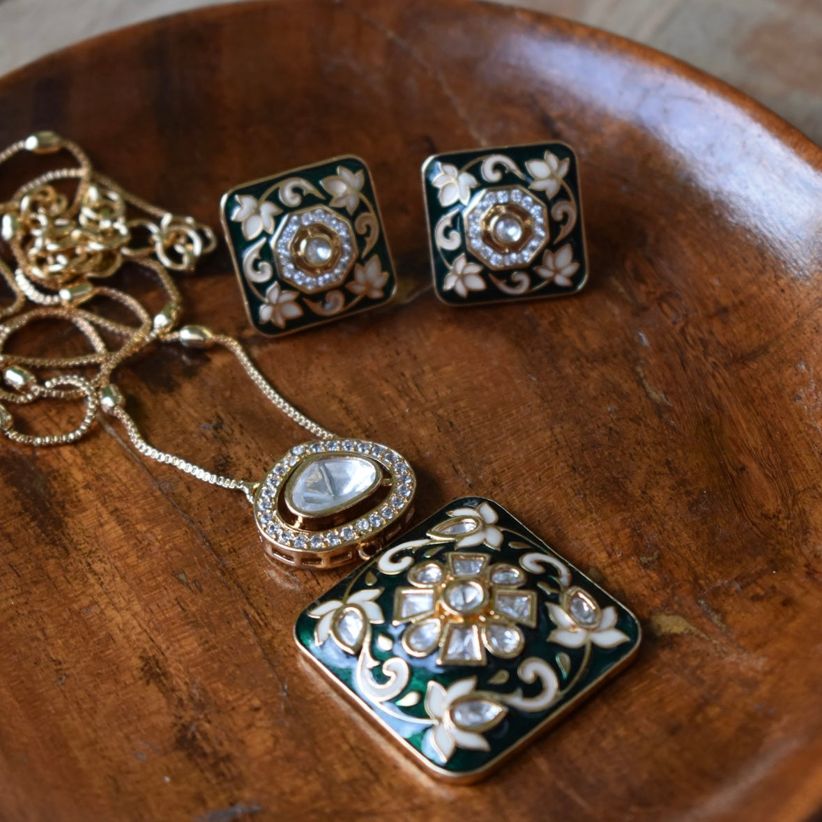 Angled view of meenakari pendant set with kundan accents and enamel detailing
