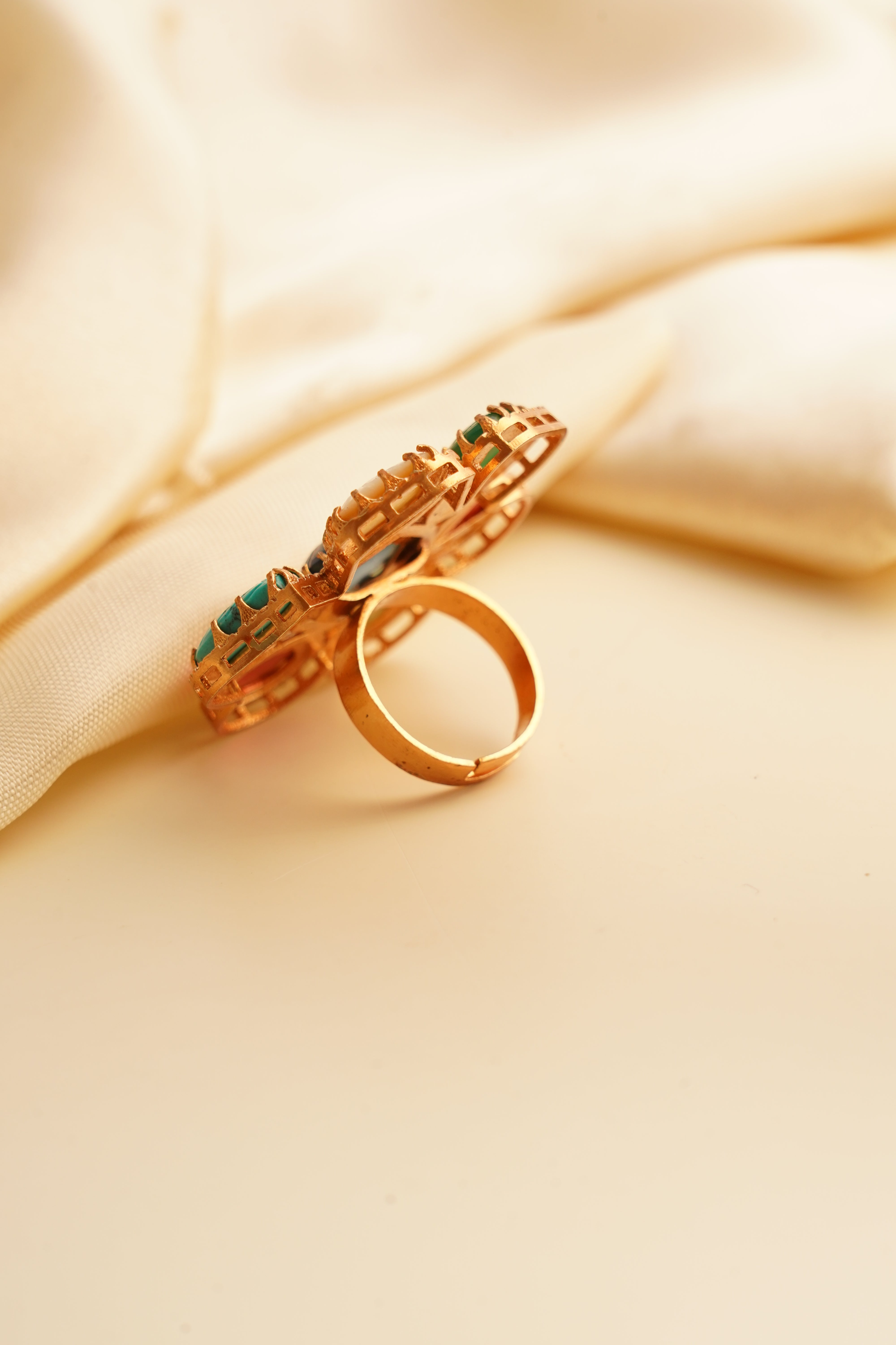 Side view of navratna ring showing carved bezel and radiant antique gold finish