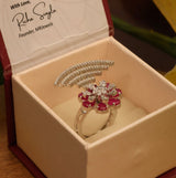 Angled side view of floral statement ring with shimmering diamonds and red stones