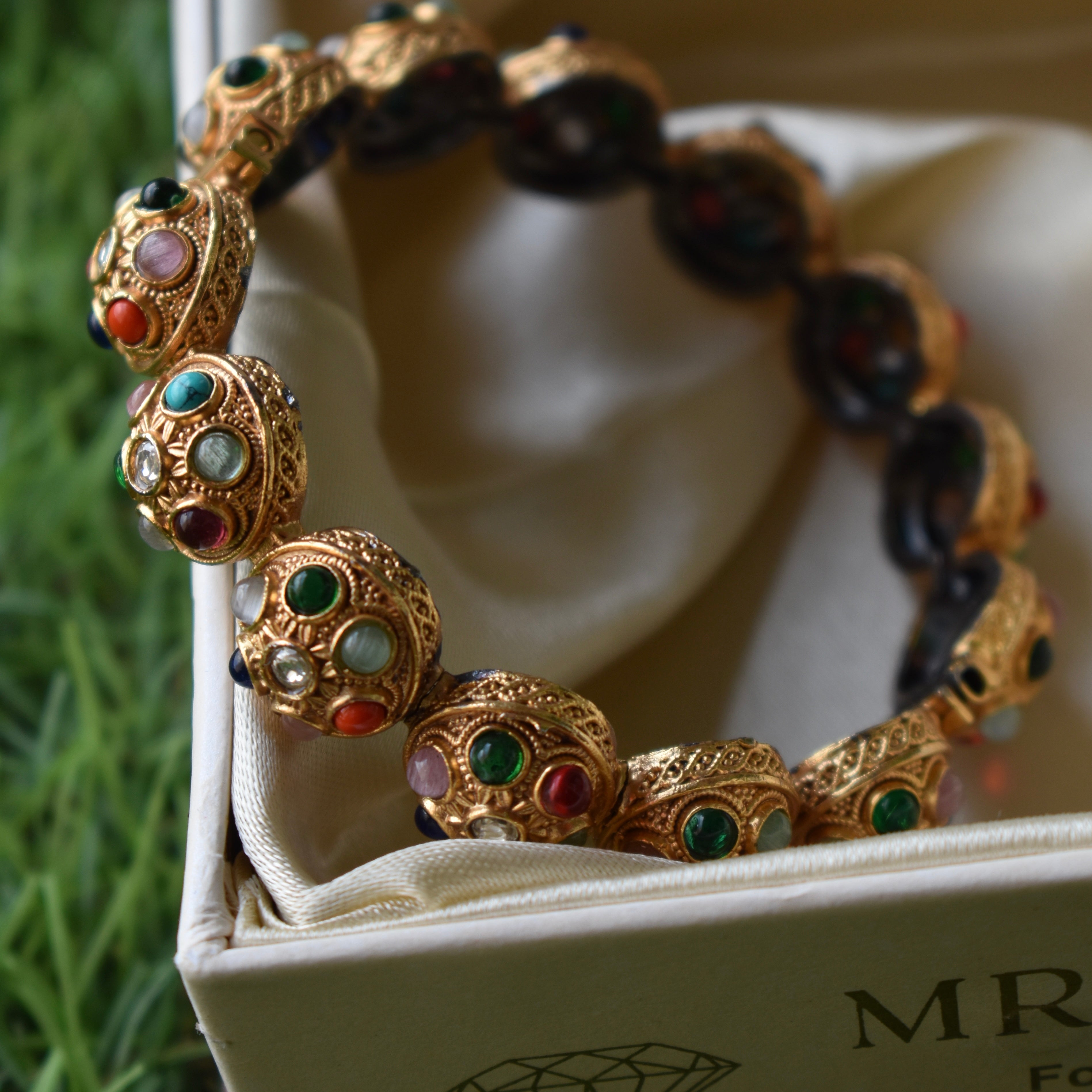 Gold-plated Navratna bangle featuring nine symbolic stones, top view