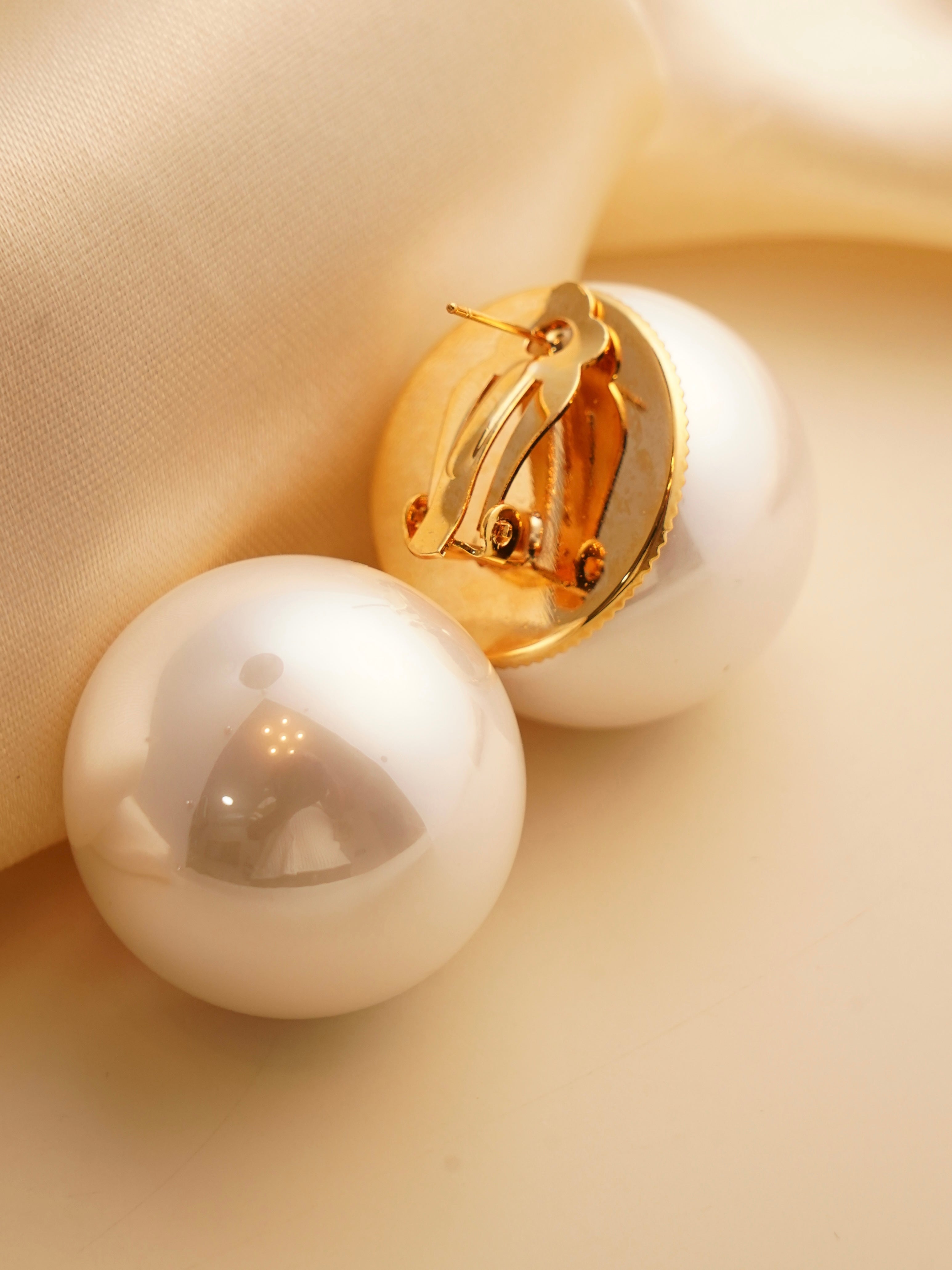 Angled close-up of 30mm large pearl stud earrings with smooth texture