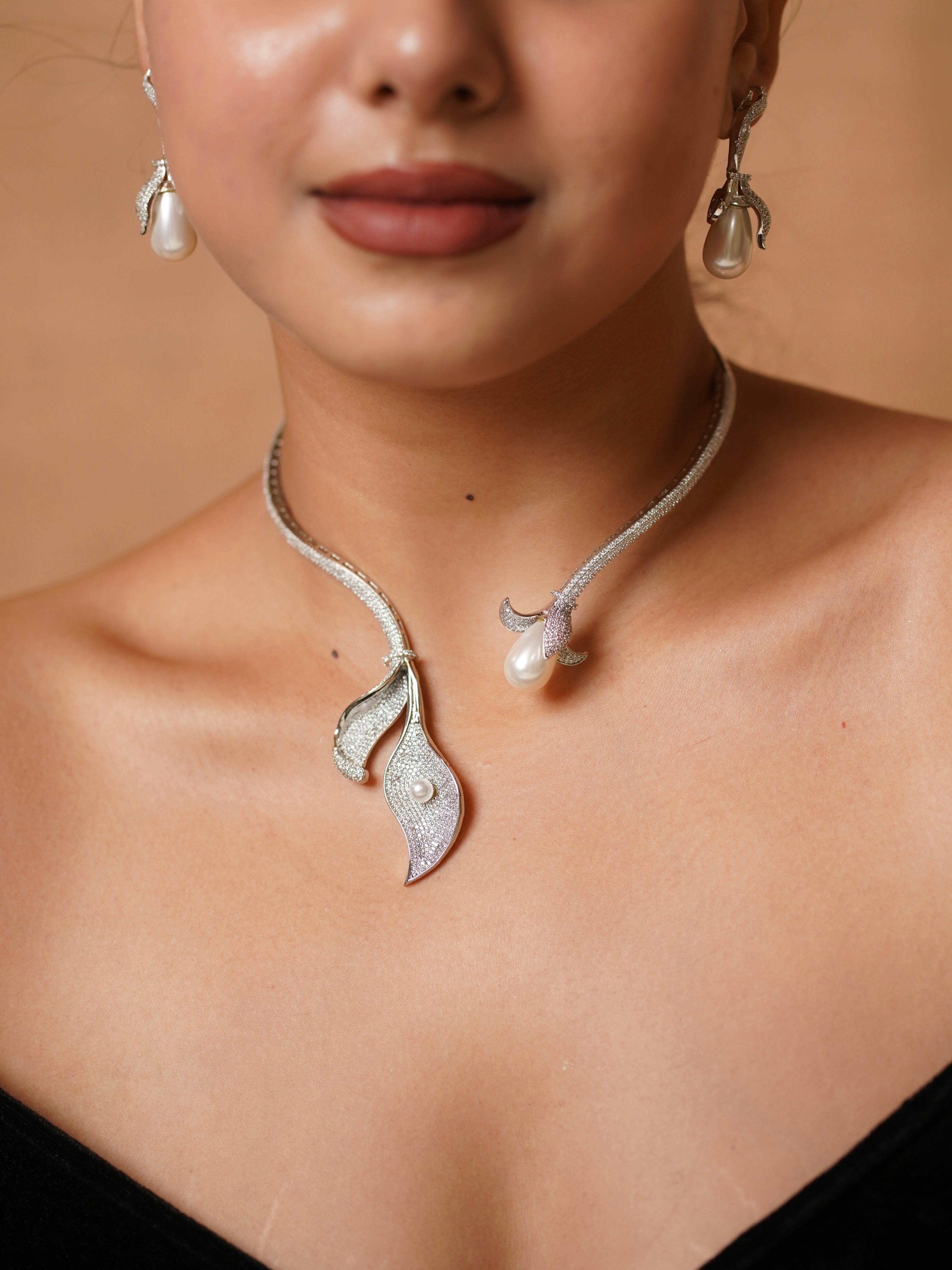 Side view of diamond-studded necklace with pearl accent in floral design