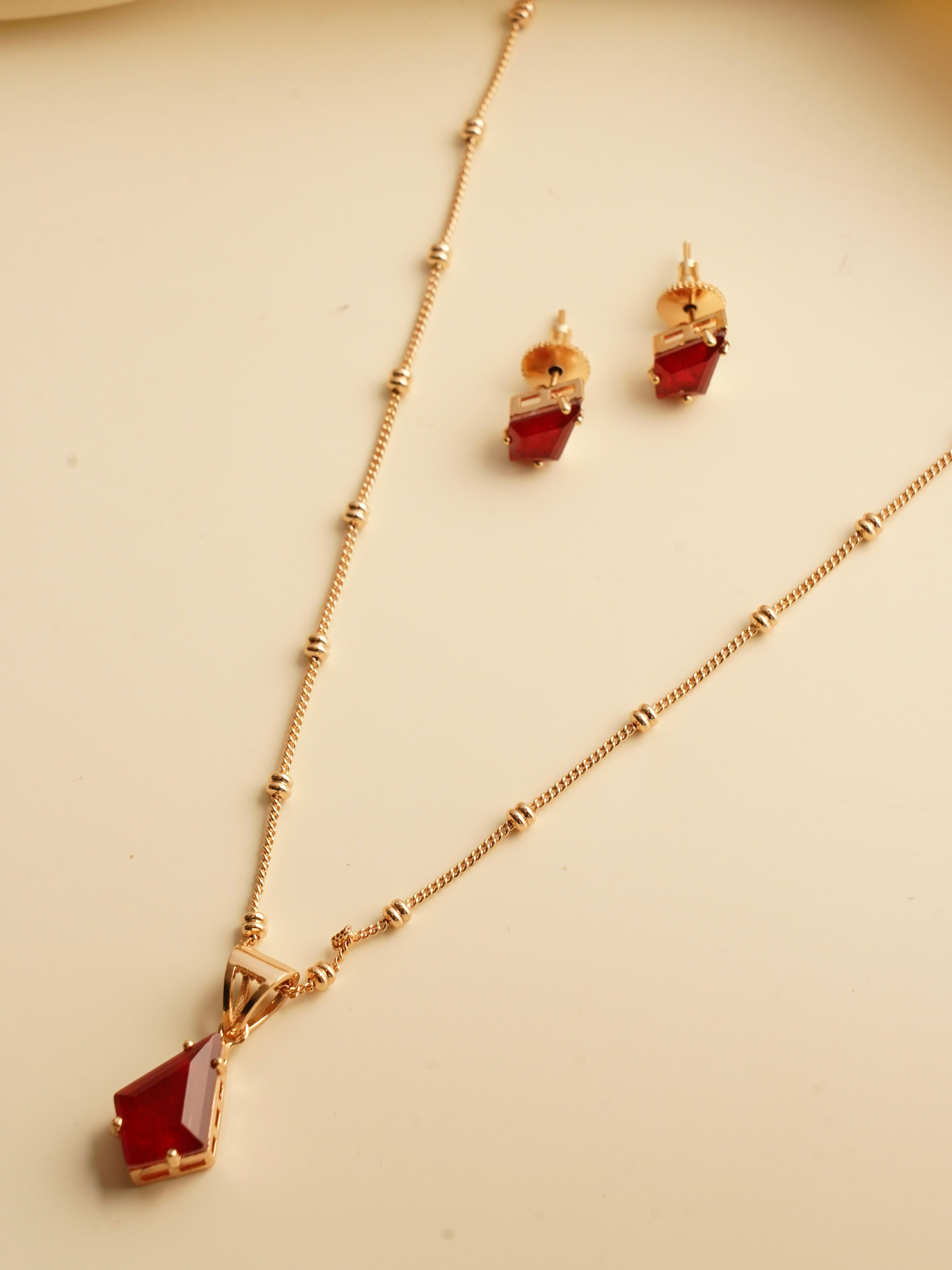 Emerald prism pendant and studs with faceted geometric stones in gold frame