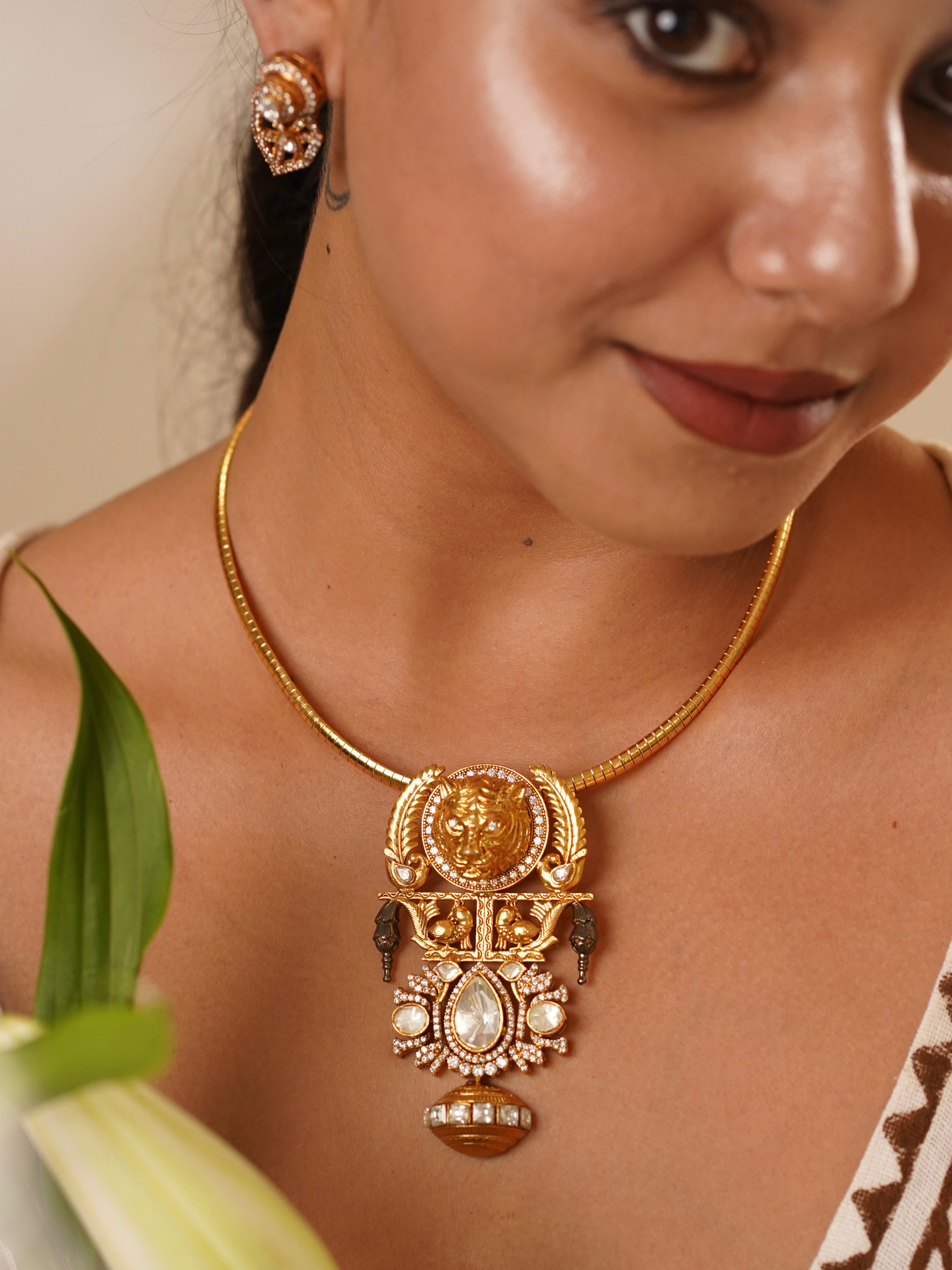 Side view of fusion necklace featuring bold pendant and designer studs with gold finish and detail