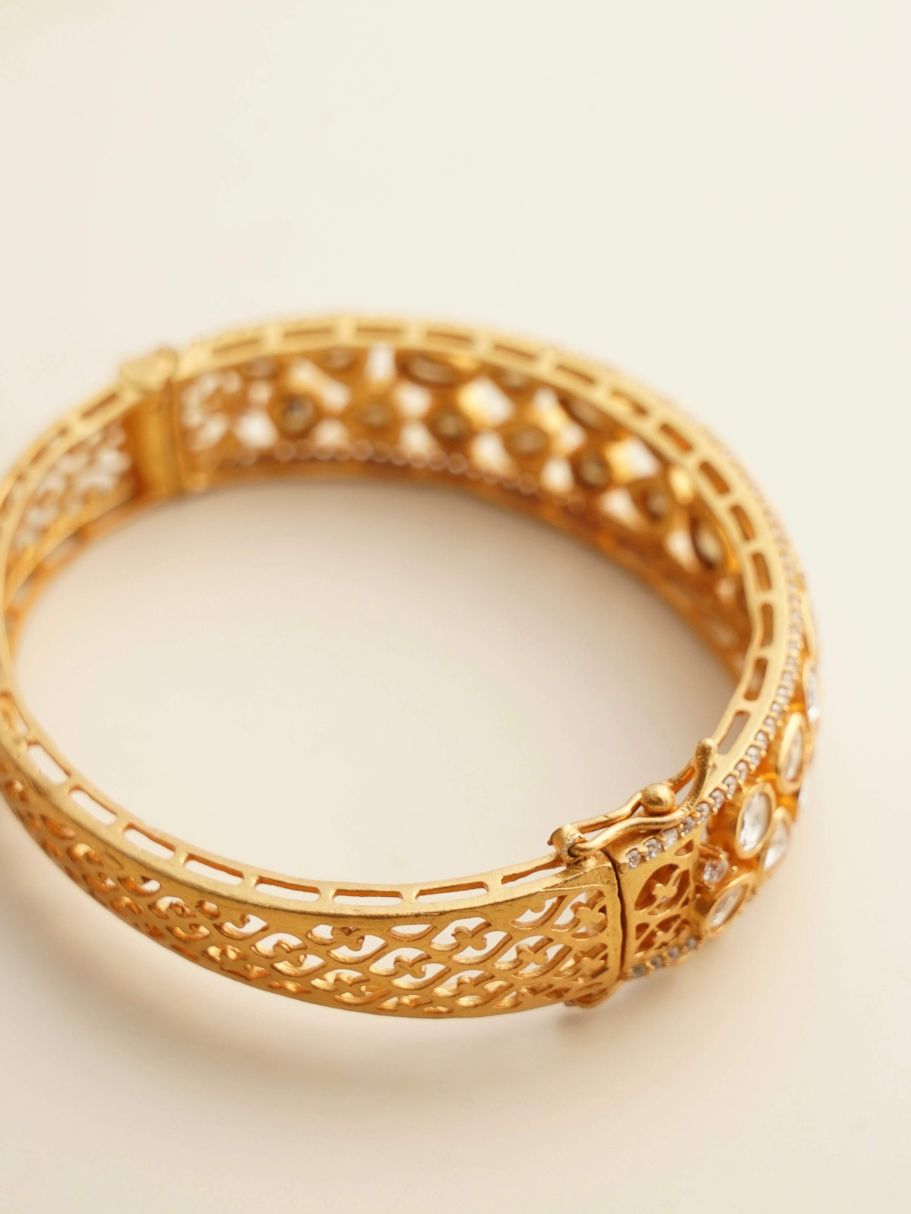 Angled view of openable moissanite kada with gold polish and filigree craftsmanship