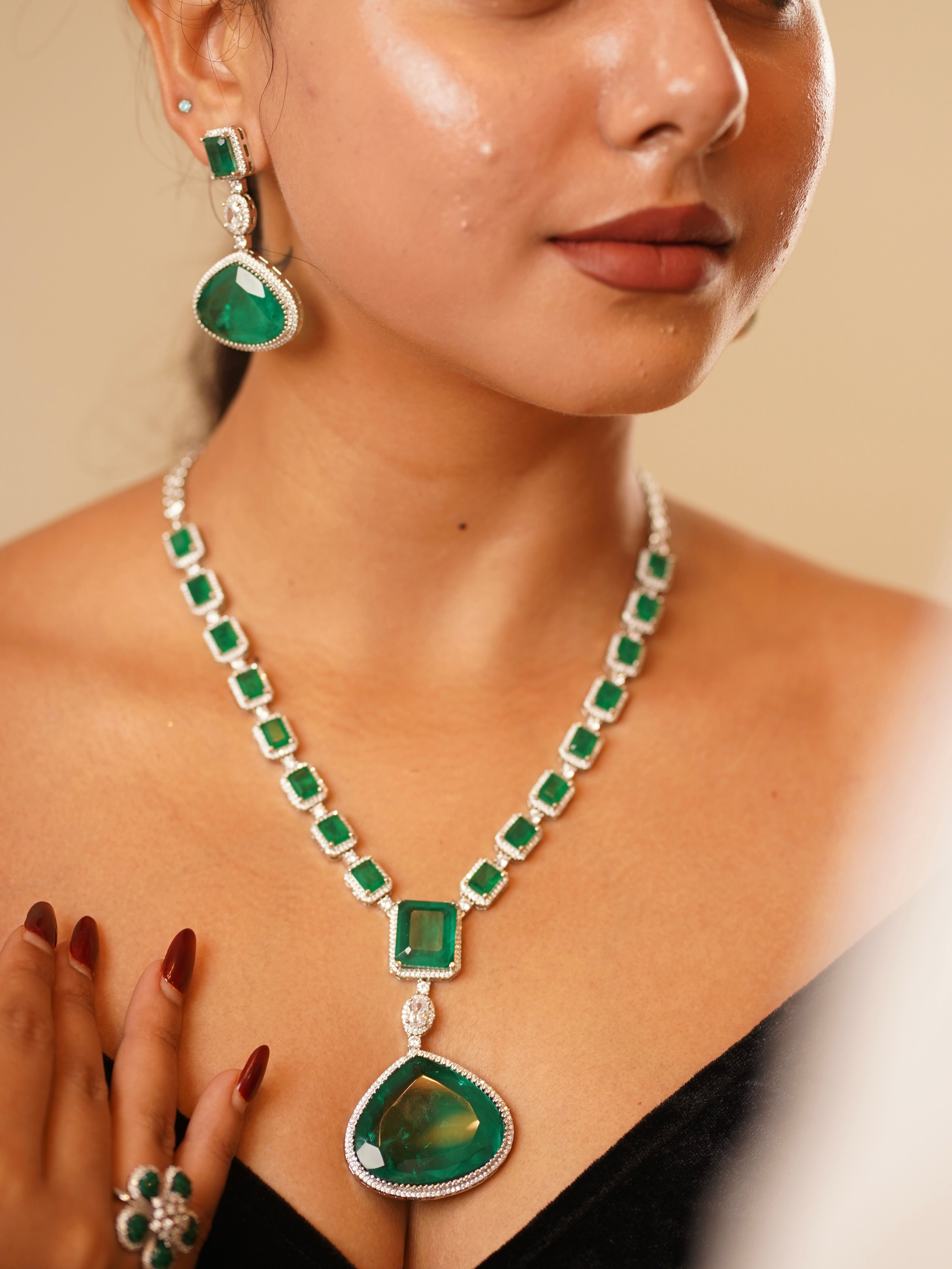 Close-up of emerald grandeur necklace featuring floral cocktail ring and pendant