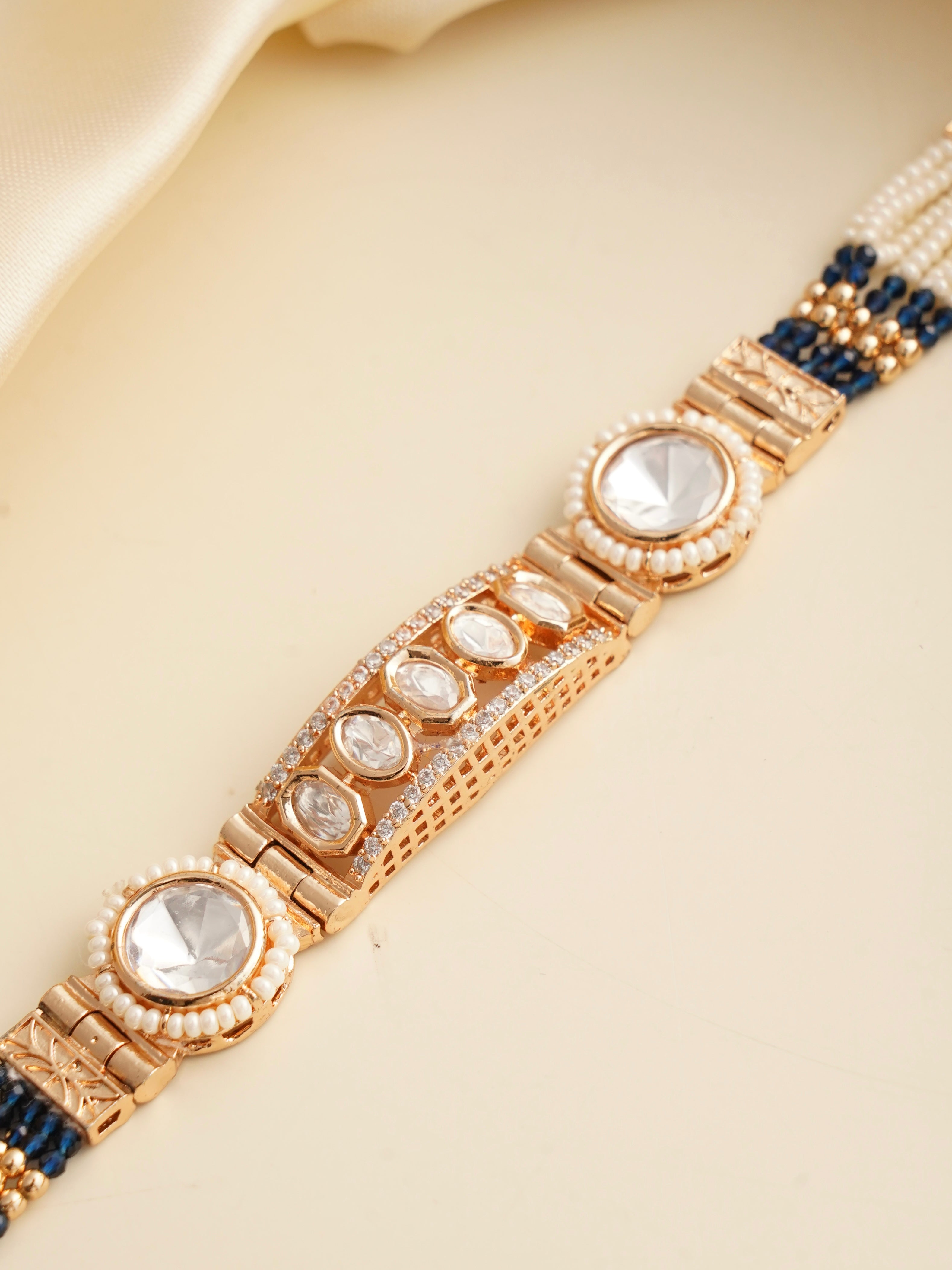 Angle view of kundan rakhi showcasing gold bezel and ivory pearls