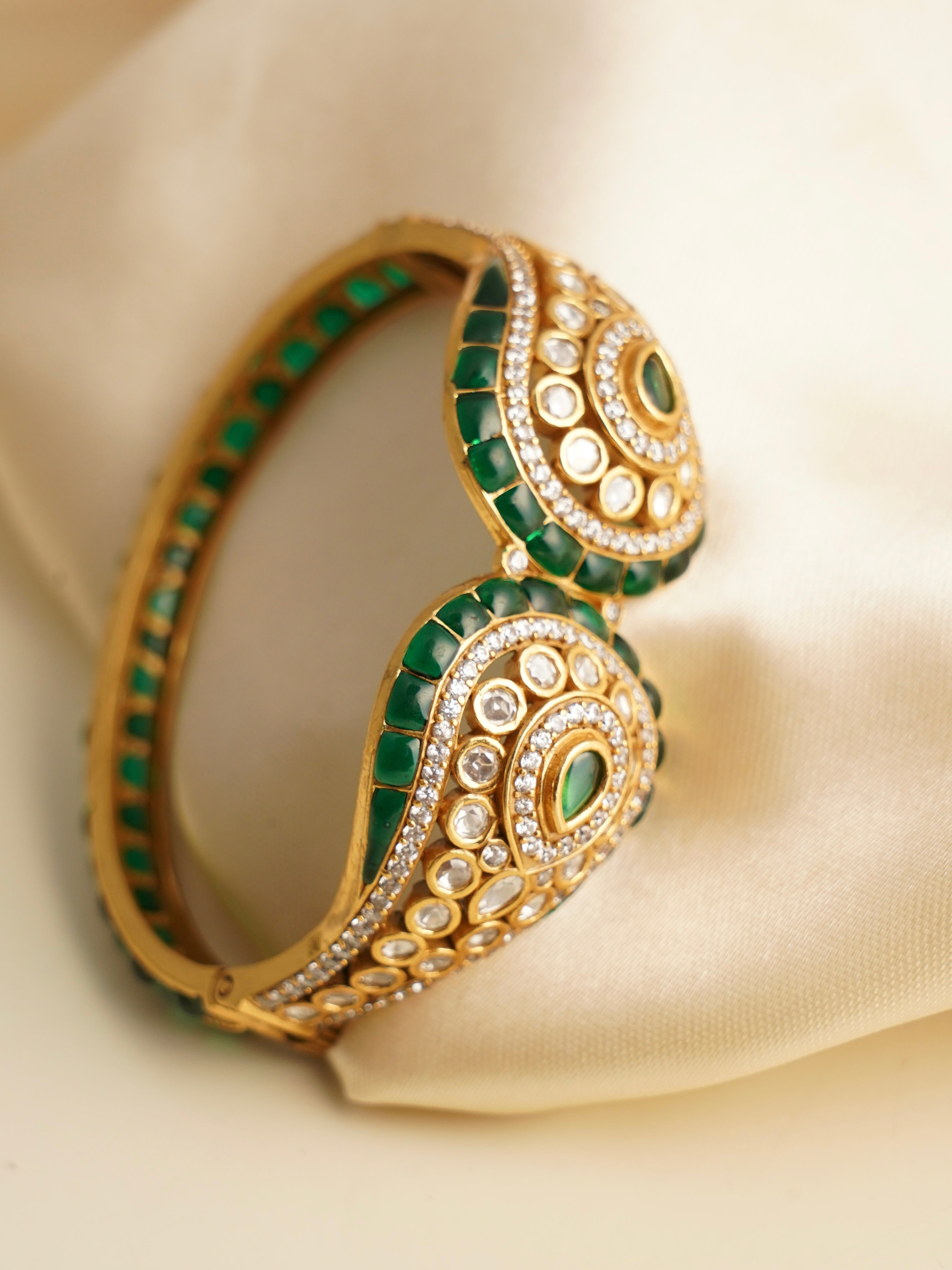Front view of emerald kada showing teardrop design with intricate polki stones and enamel accents